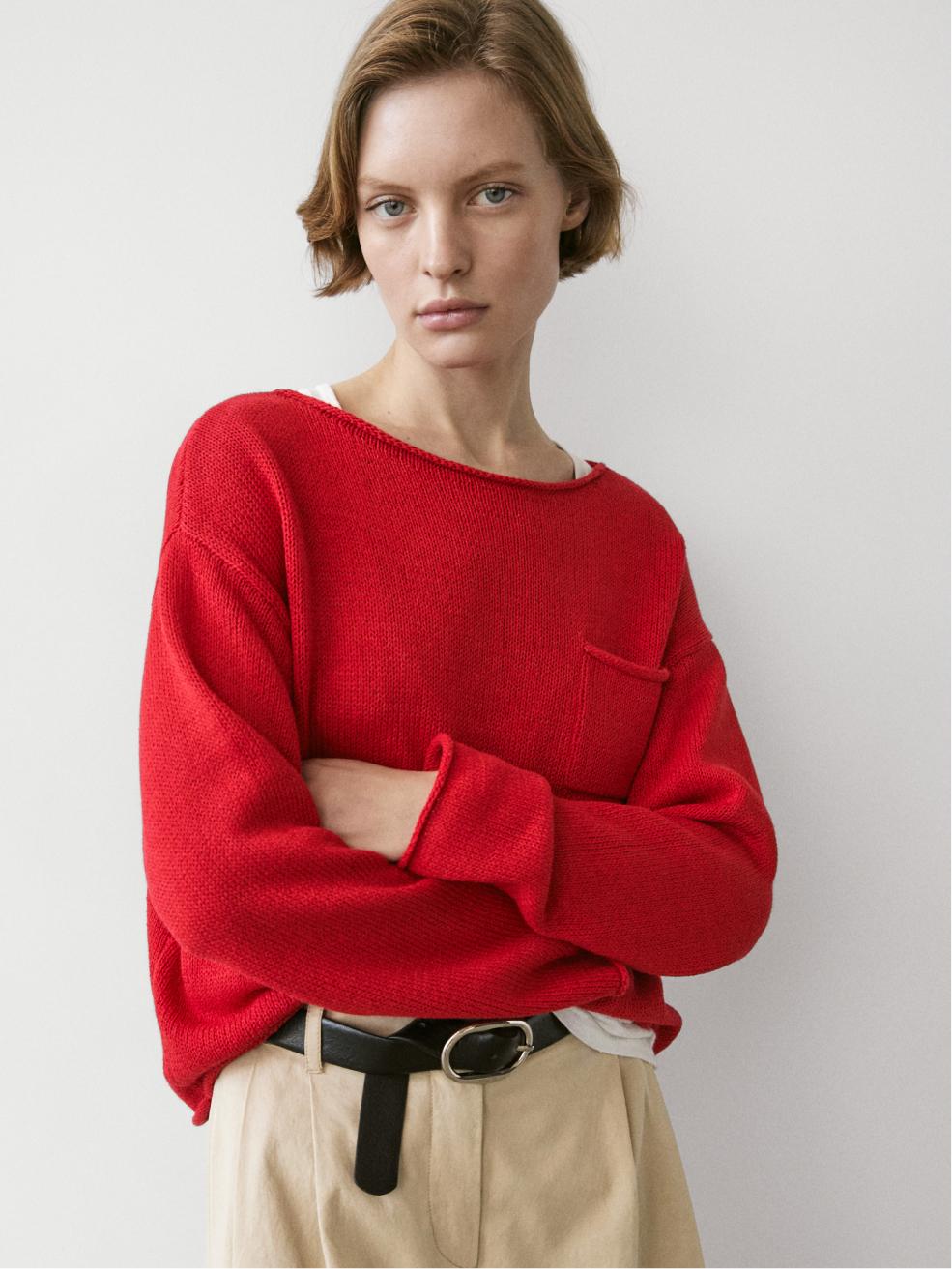 Μεσαίο πλάνο κόκκινου πουλόβερ με μπροστινή τσέπη, στρογγυλή λαιμόκοψη και μακριά μανίκια.