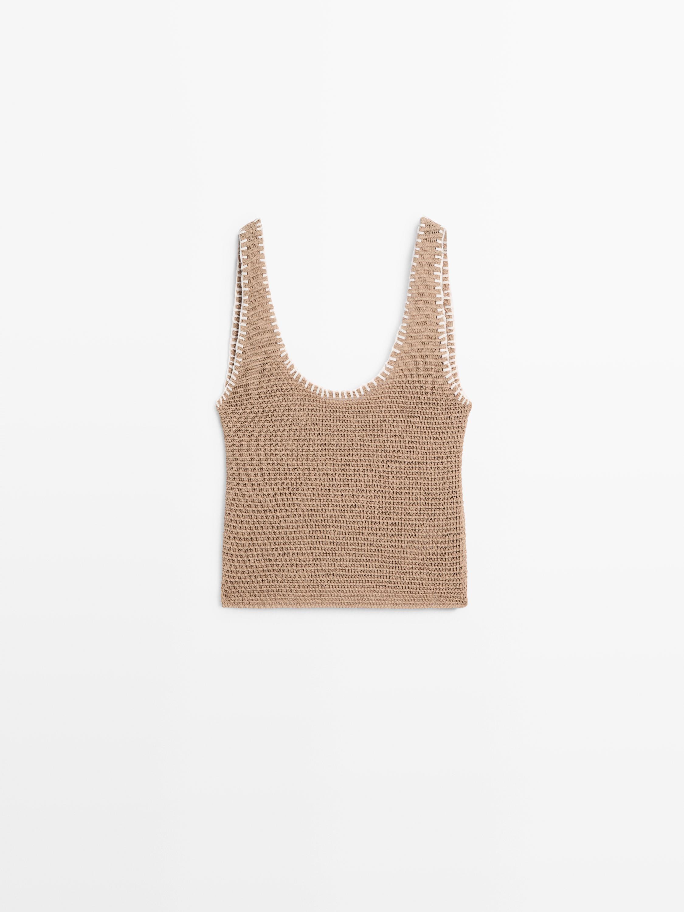 Mặt trước áo croptop màu be dệt kim có cổ tròn và viền trắng ở dây áo.