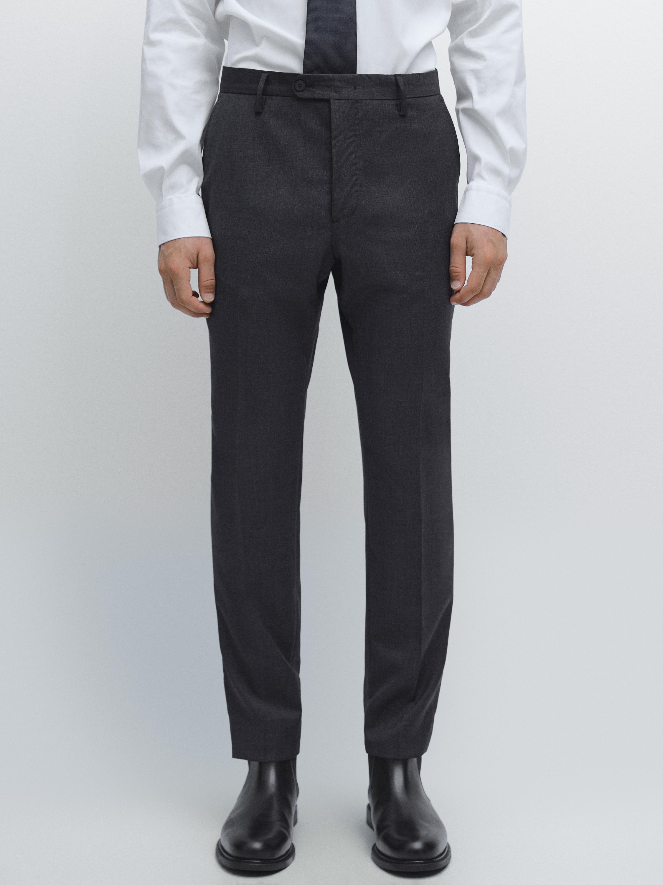 Ensemble de pantalon de costume bleu marine avec poches latérales et fermeture boutonnée, combiné avec une chemise blanche et une cravate noire.