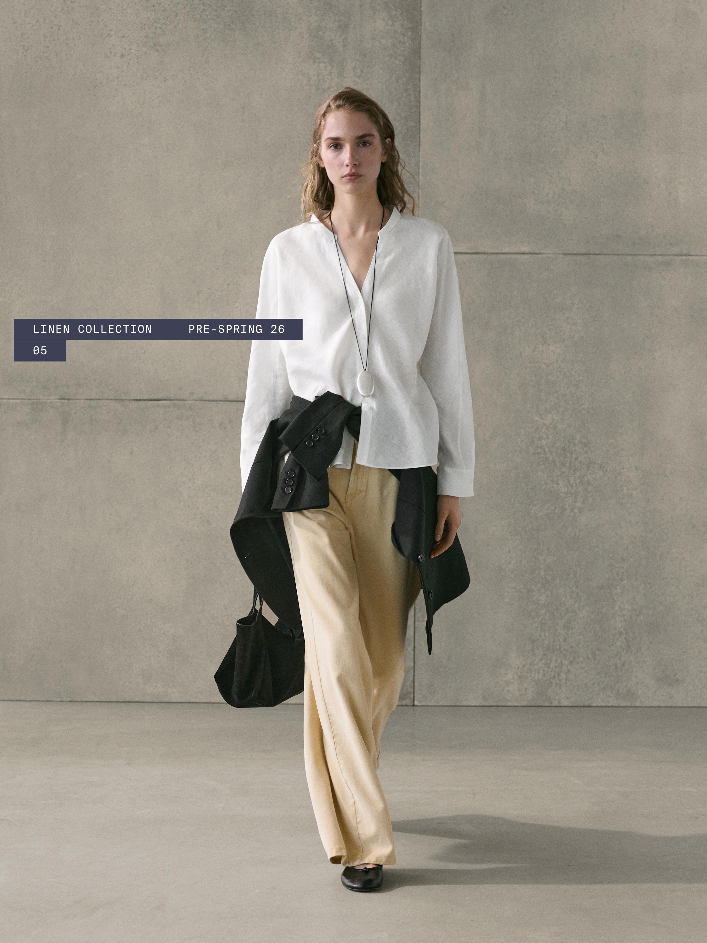 סט הכולל חולצה לבנה עם צווארון סיני, מכנסיים רחבים בצבע בז', ז'קט שחור קשור ותיק שחור. כיתוב "LINEN COLLECTION PRE-SPRING 26".