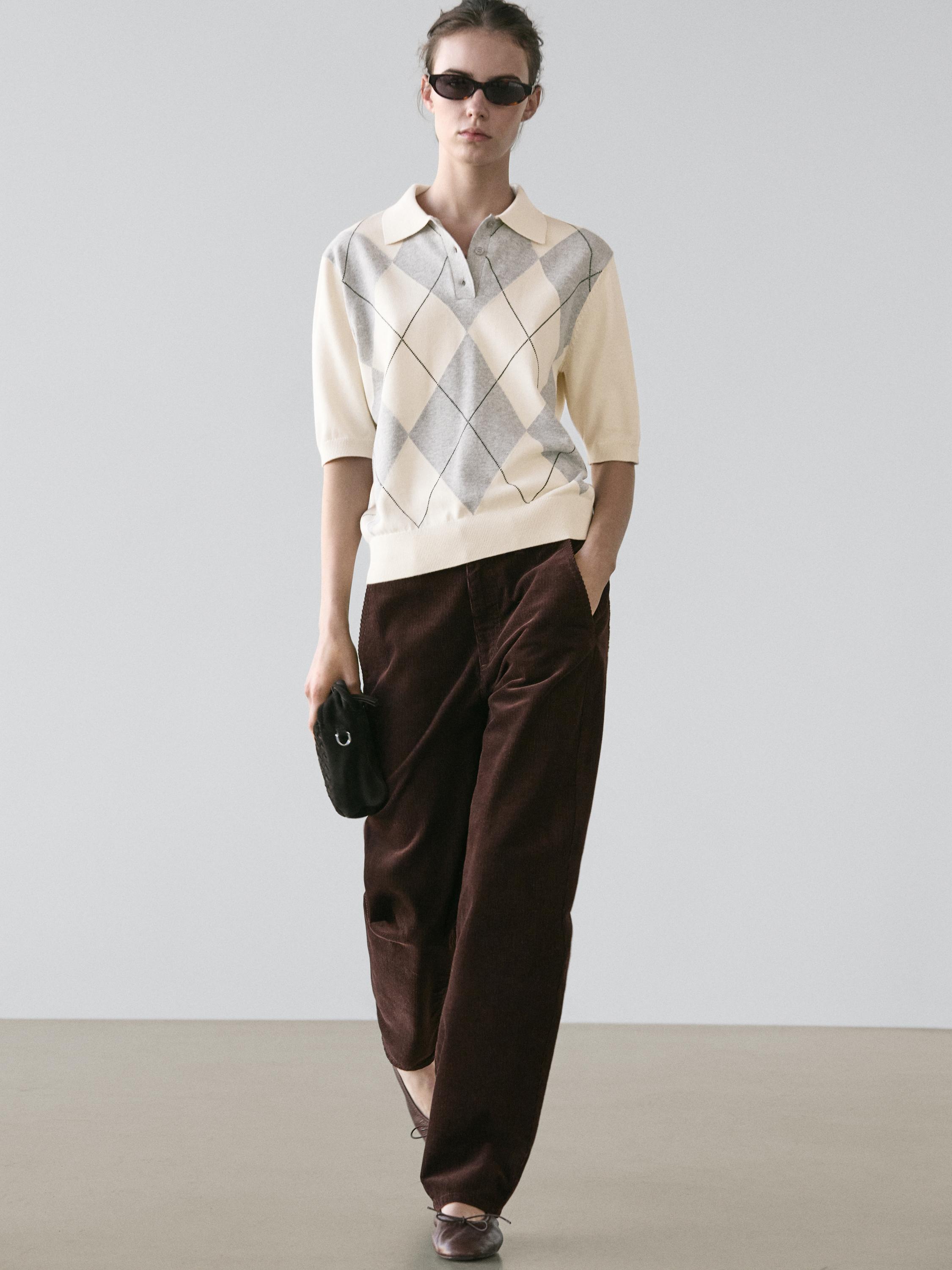 طقم سويتر بلون بيج مع أشكال معينية رمادية وبنطلون بني واسع.