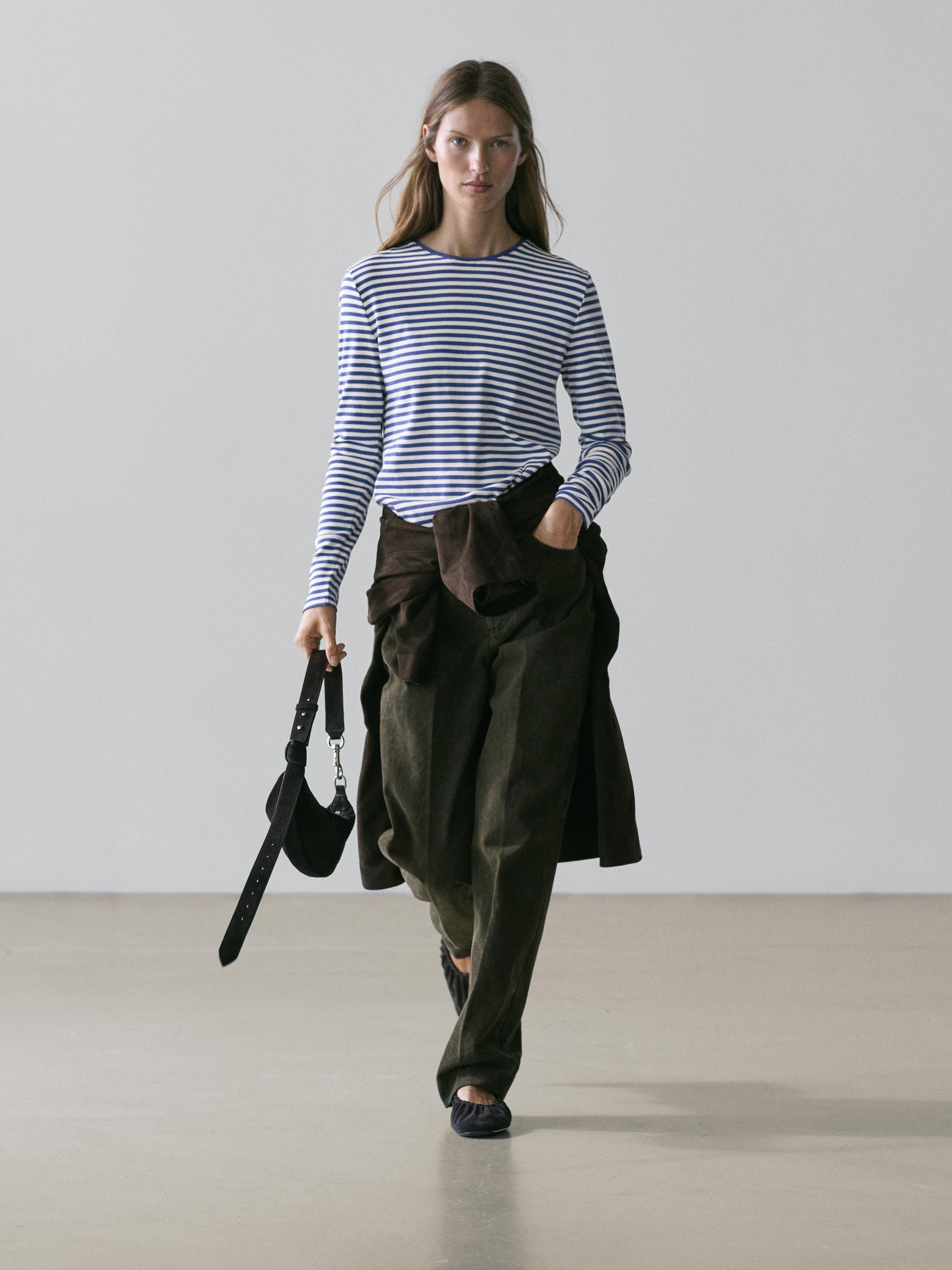 Ensemble composé d'un t-shirt à rayures bleu marine et blanc à manches longues, d'un pantalon marron ample et d'un sac noir.