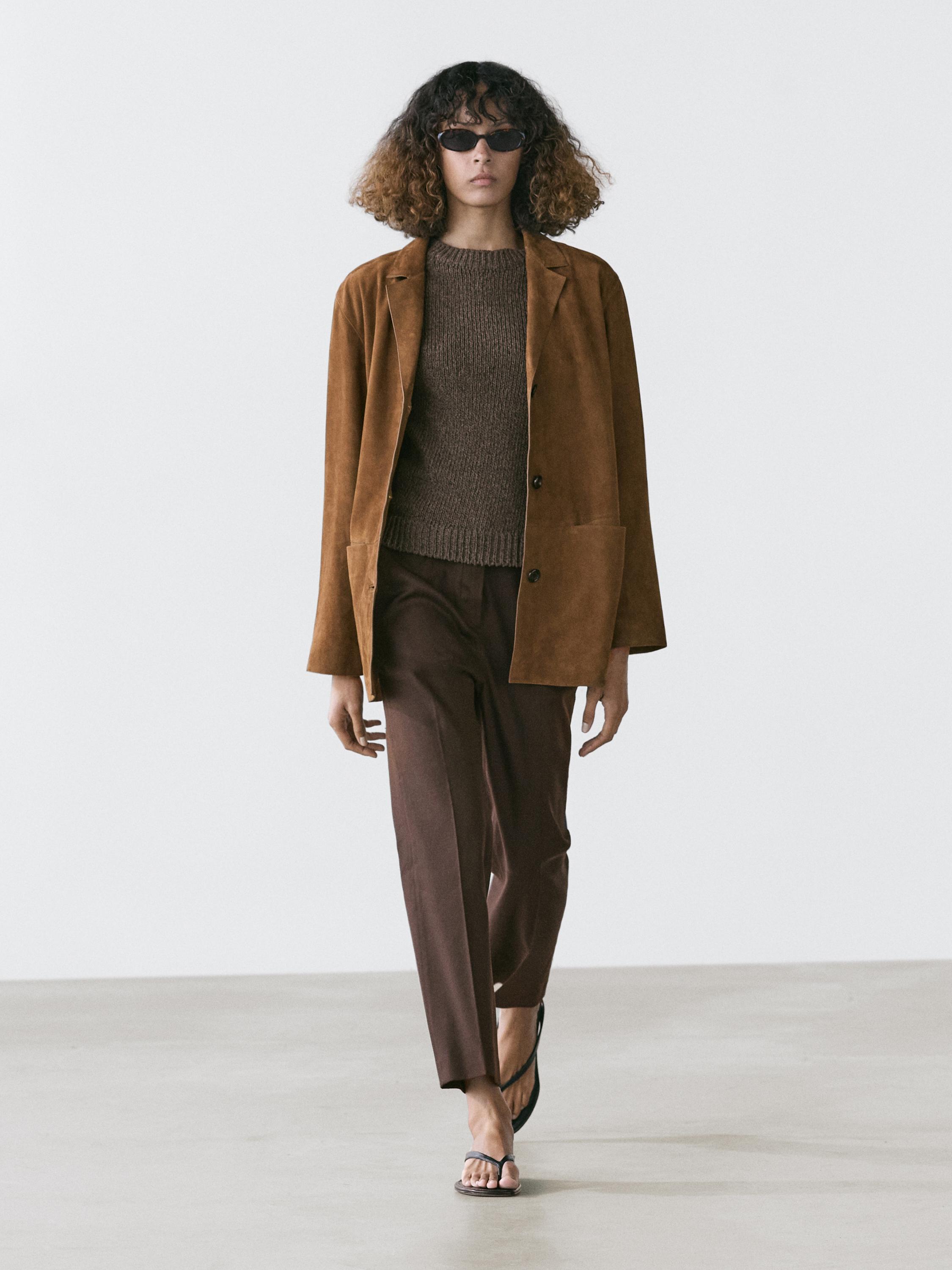 Conjunto de casaco castanho com bolsos, camisola castanha escura e calças castanhas direitas.