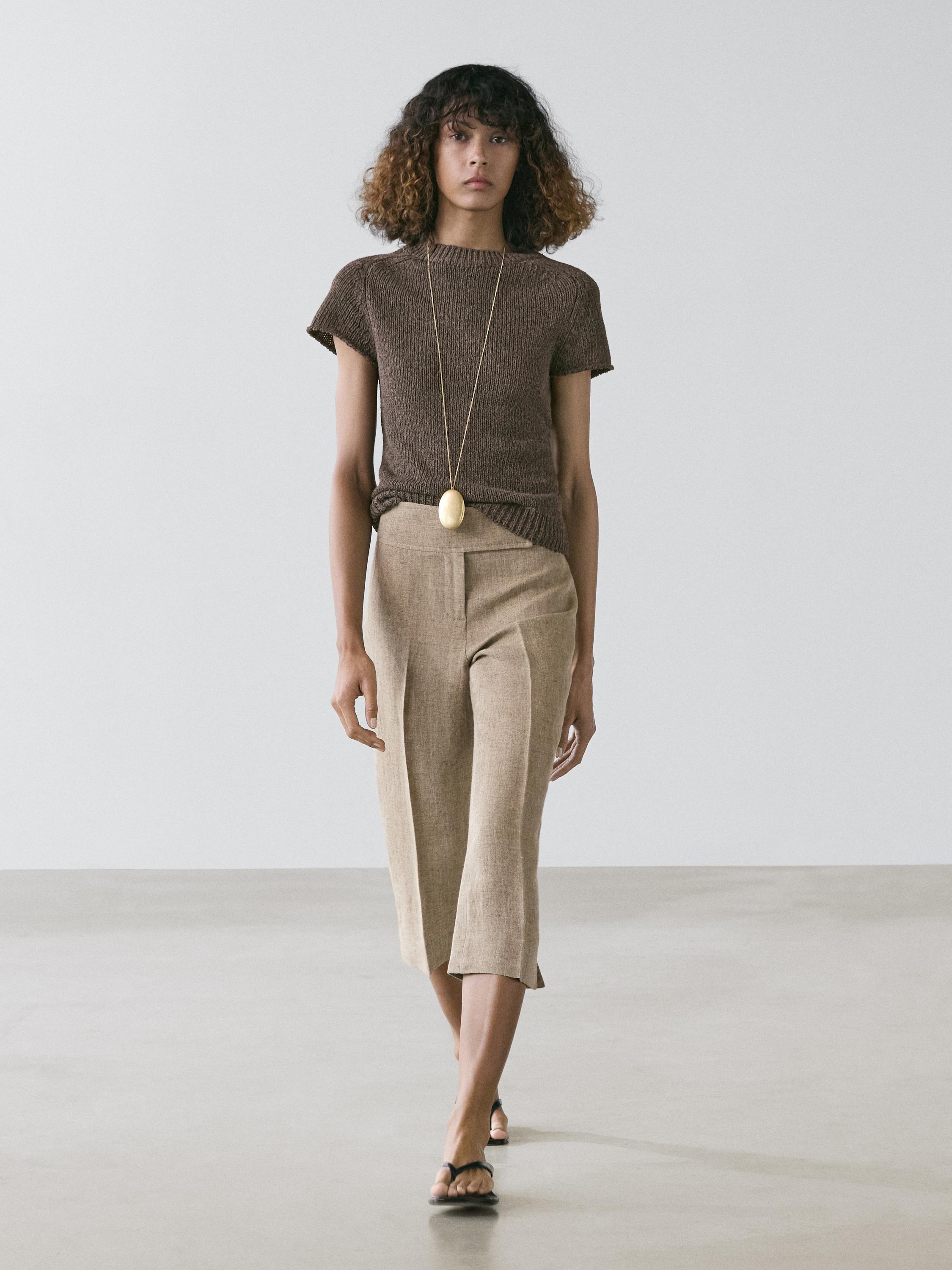 Conjunto de jersey café de punto de manga corta y pantalones beige de pierna ancha.