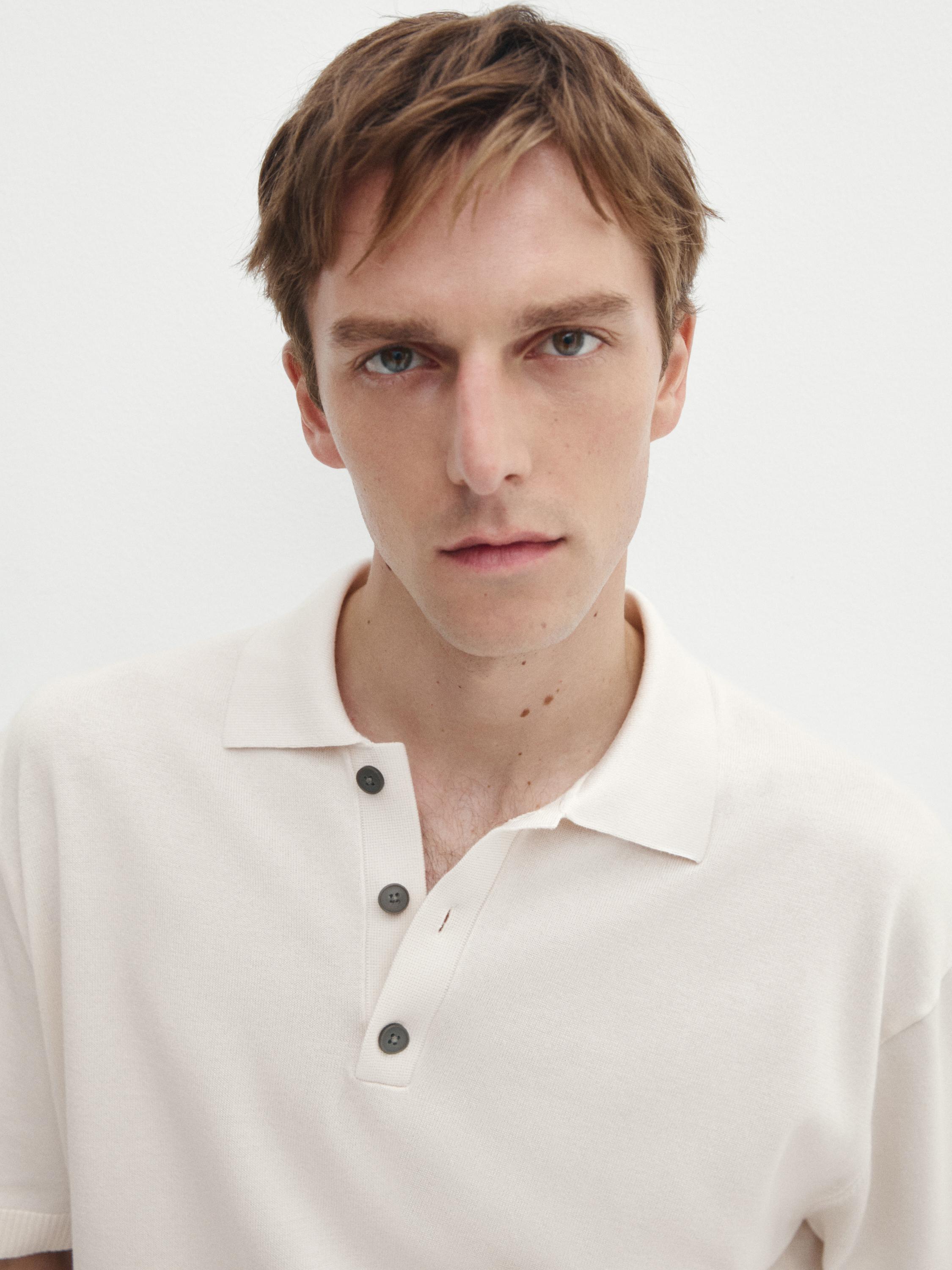 Gros plan d'un polo blanc avec des boutons foncés et un col classique.