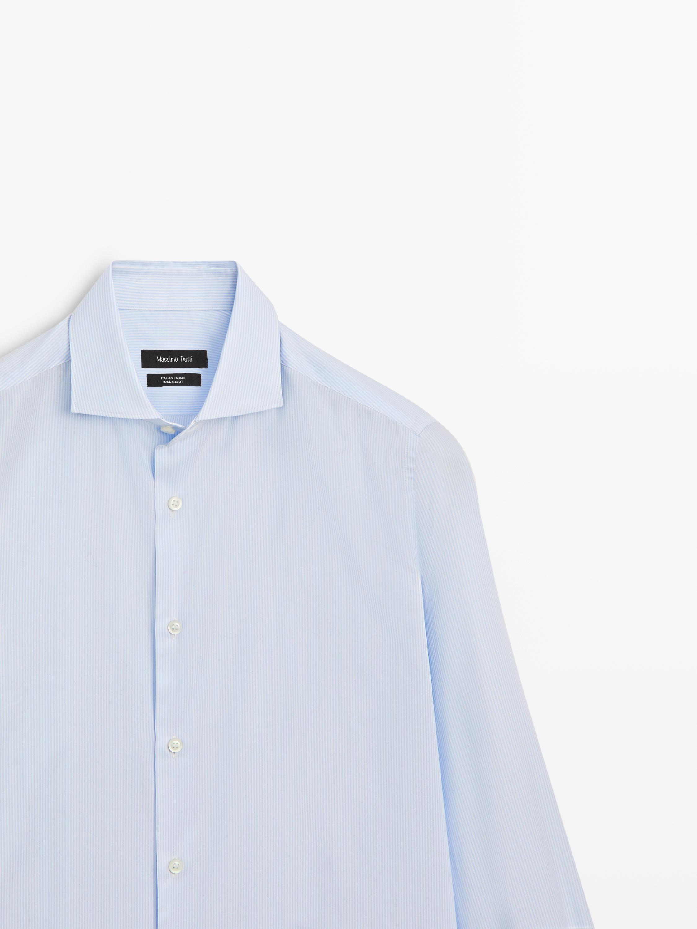 "Plano medio de camisa azul celeste de manga larga con cuello clásico y botonadura frontal visible."