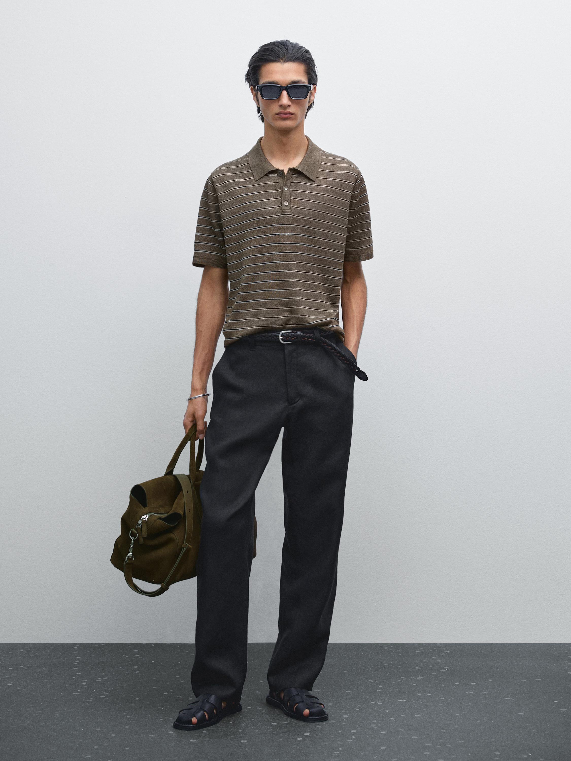 طقم يتكون من قميص بولو بني مخطط، بنطلون داكن، وصندل أسود. يحمل حقيبة بنية.
