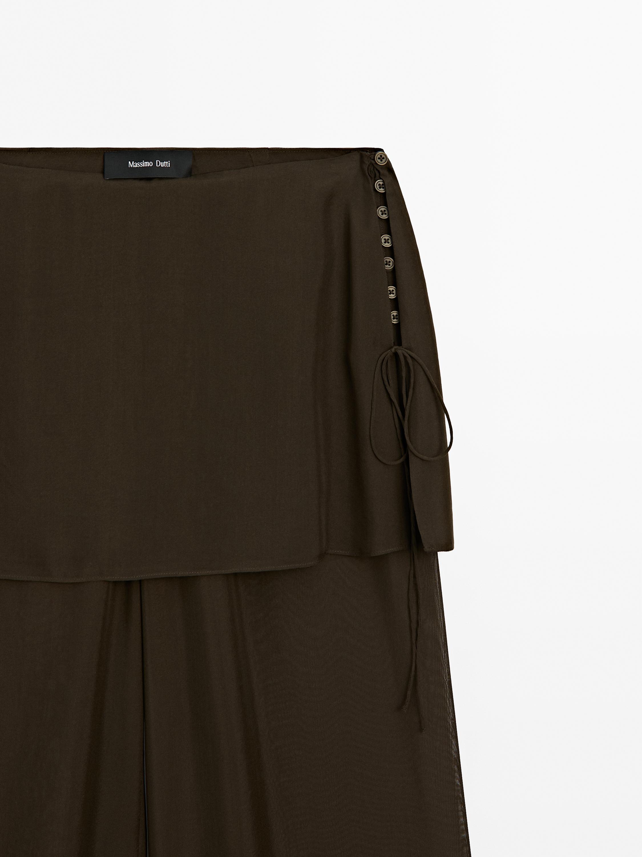 Close-up of the top of a dark brown skirt with side buttons.