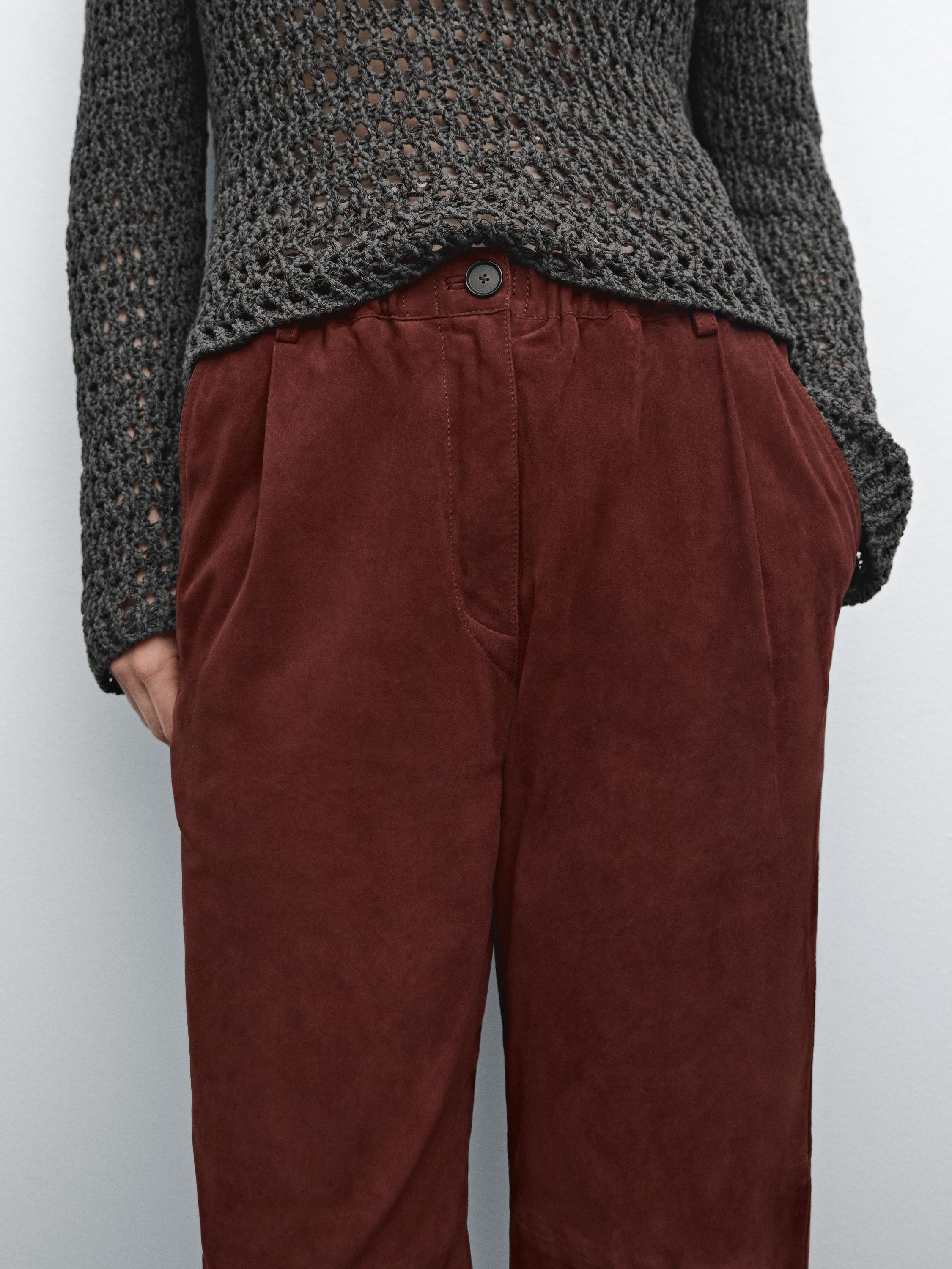 Gros plan sur un pantalon marron avec des poches latérales et un bouton visible.