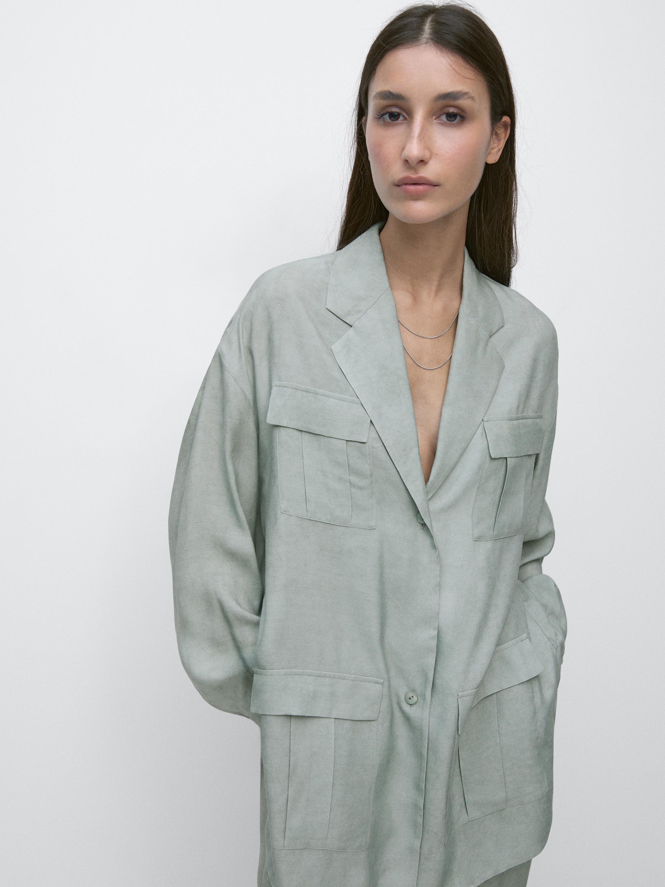 لقطة متوسطة لقميص خارجي بلون الفستق مع جيوب أمامية وقلاب، وزر ظاهر وقصة فضفاضة.