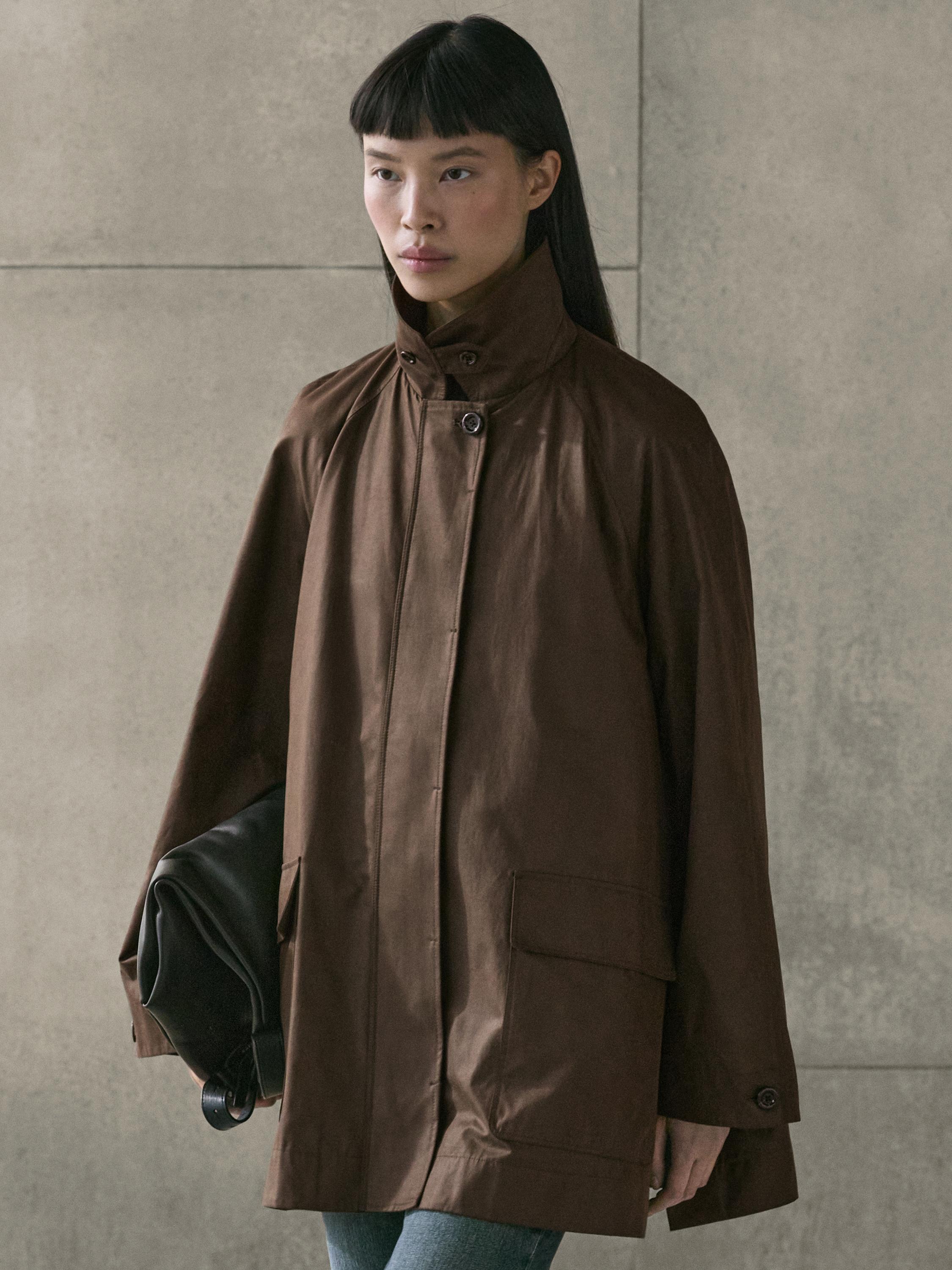 لقطة متوسطة لمعطف بني داكن بياقة عالية وجيوب أمامية بغطاء.