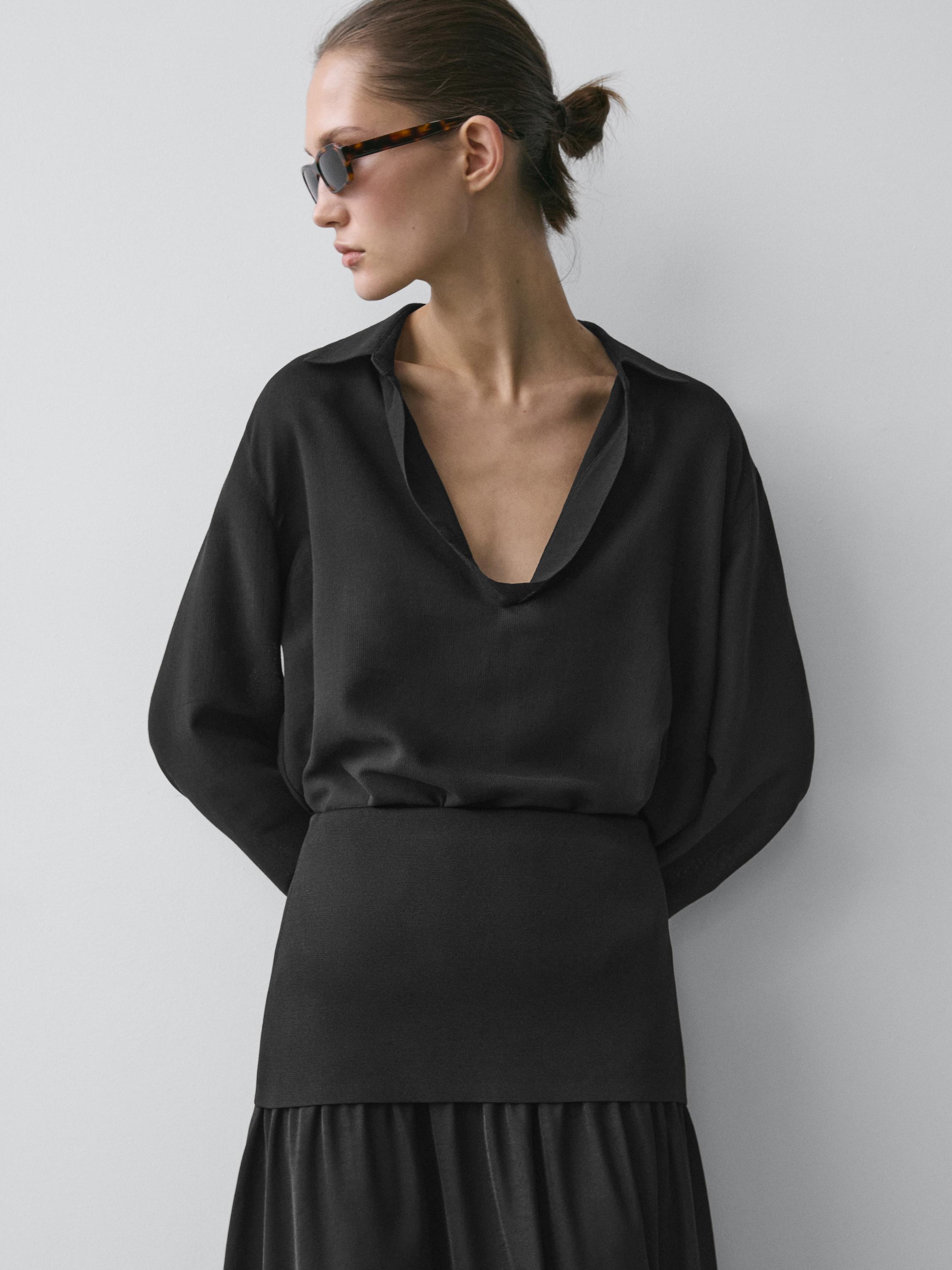 plaintext Μεσαίο πλάνο μαύρης μπλούζας με βαθύ ντεκολτέ σε σχήμα V και μακριά μανίκια.