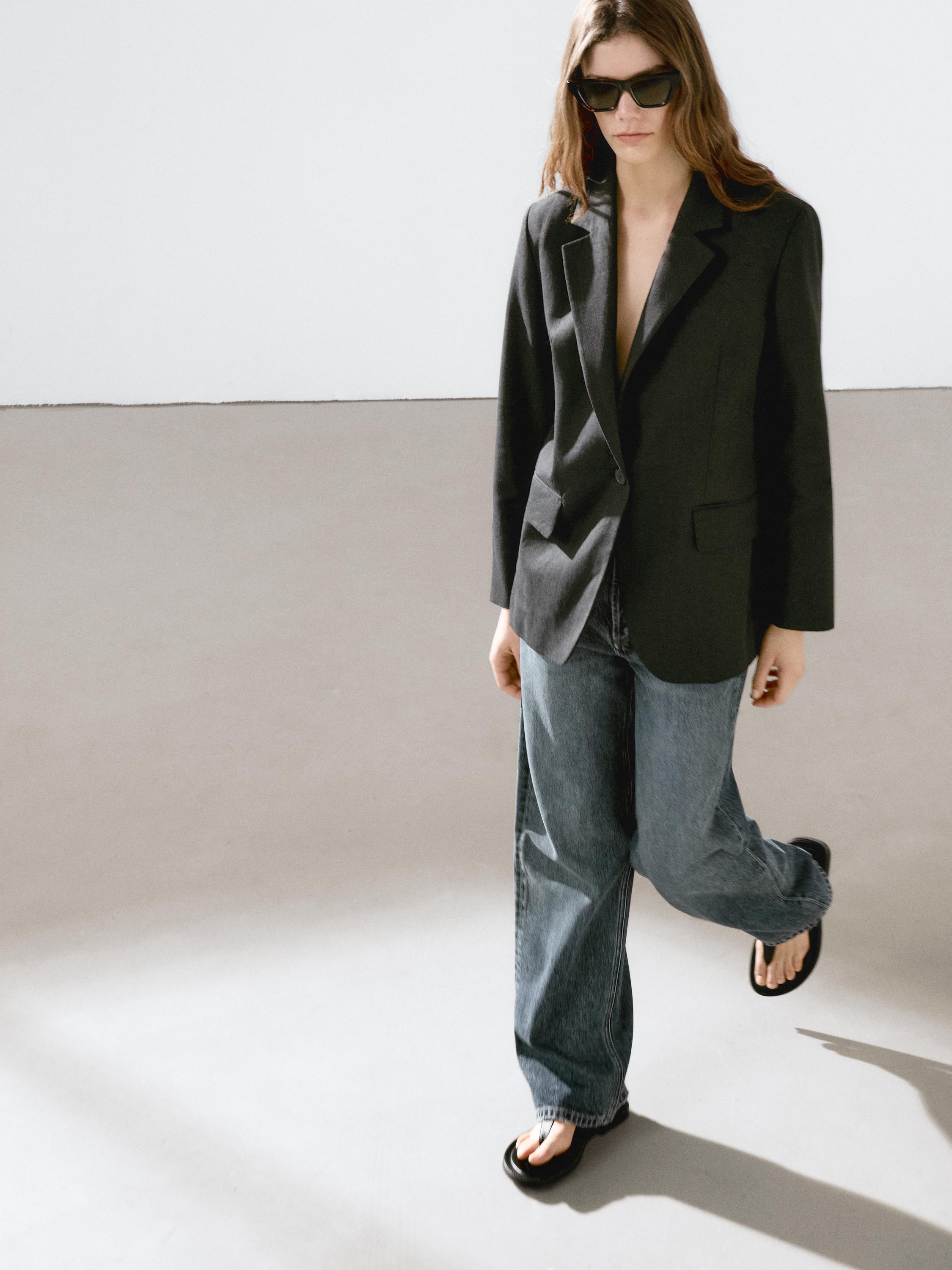 طقم بليزر أسود بجيوب وبنطلون جينز واسع.