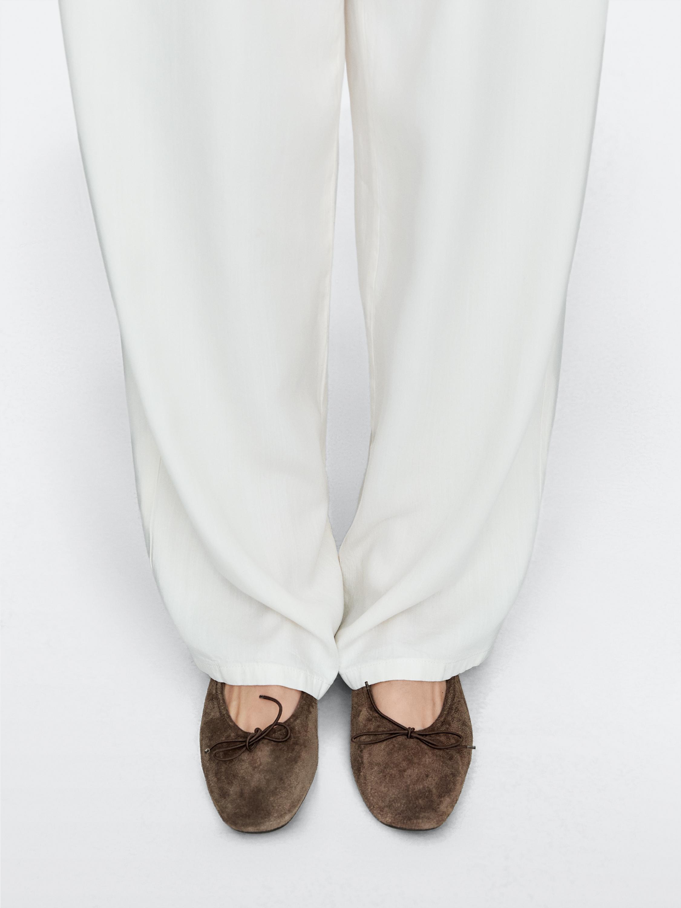 Witte broek en kaki ballerina's met ruches en strik aan de bovenkant.