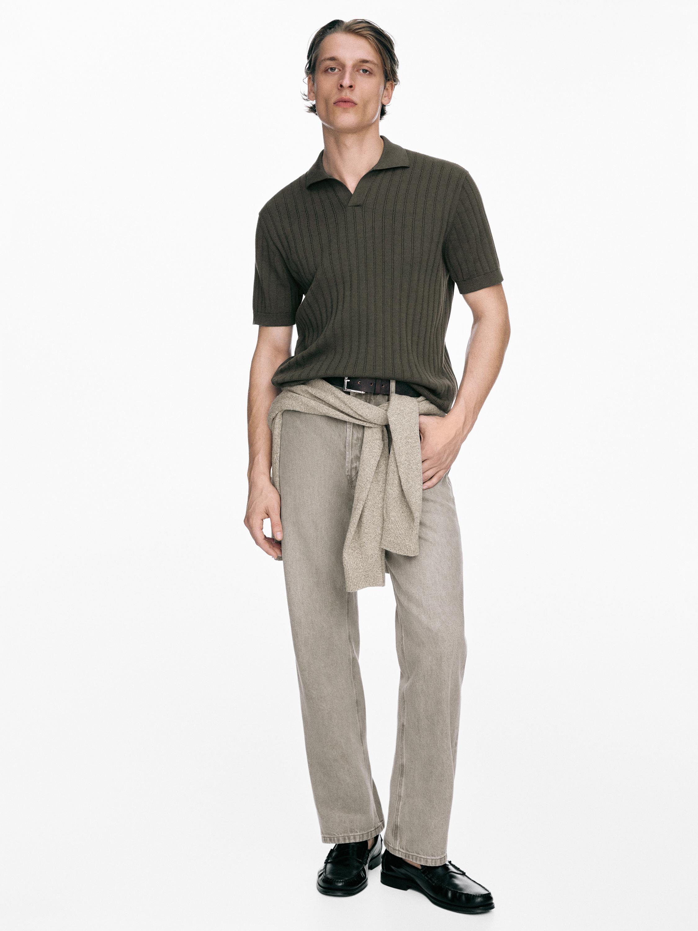 Conjunto de jersey polo caqui oscuro de punto trenzado y pantalones beige, con suéter atado a la cintura.
