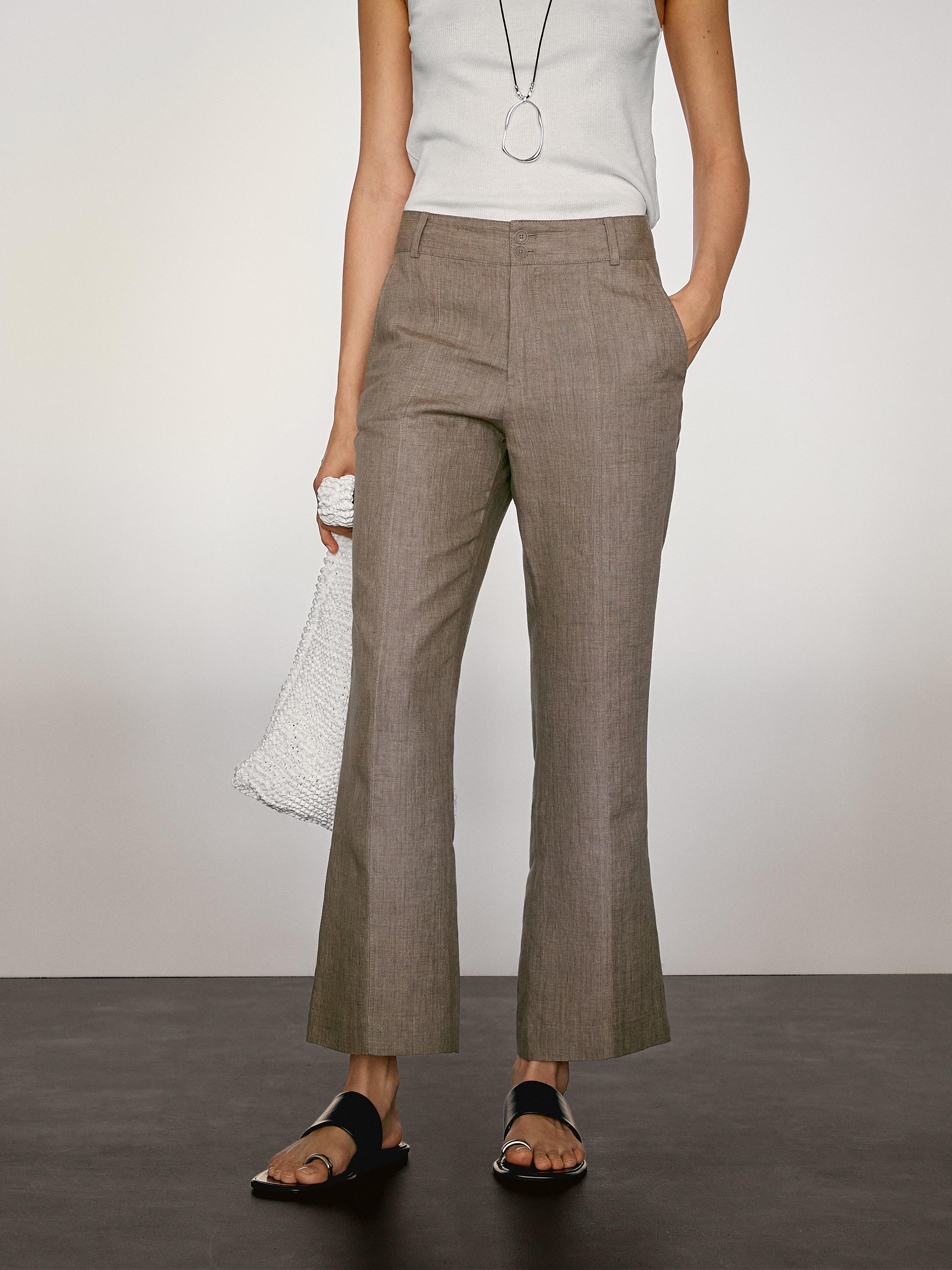 طقم يتكون من بنطلون بني بقصة مستقيمة مع جيوب جانبية و توب أبيض بدون أكمام.