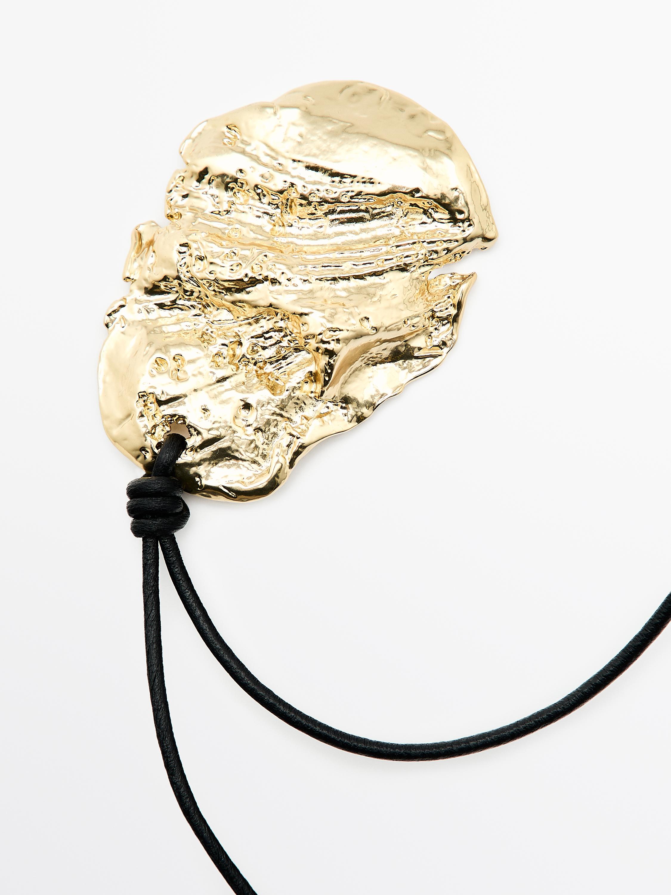 Düzensiz dokulu ve siyah kordonlu altın kolye detayı.