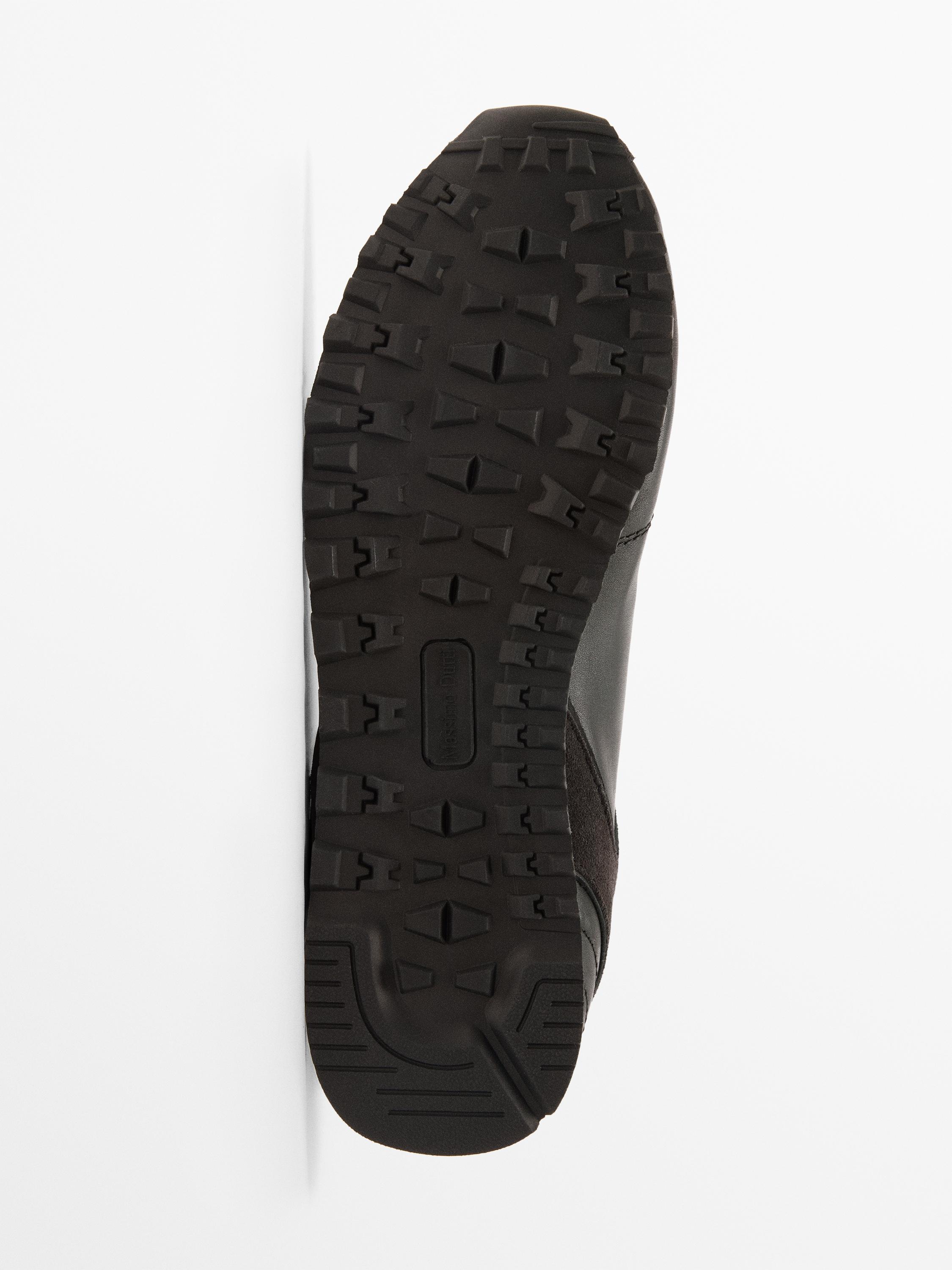 Detalle de la suela de una zapatilla negra con diseño de tracción y texto "Made in Italy".