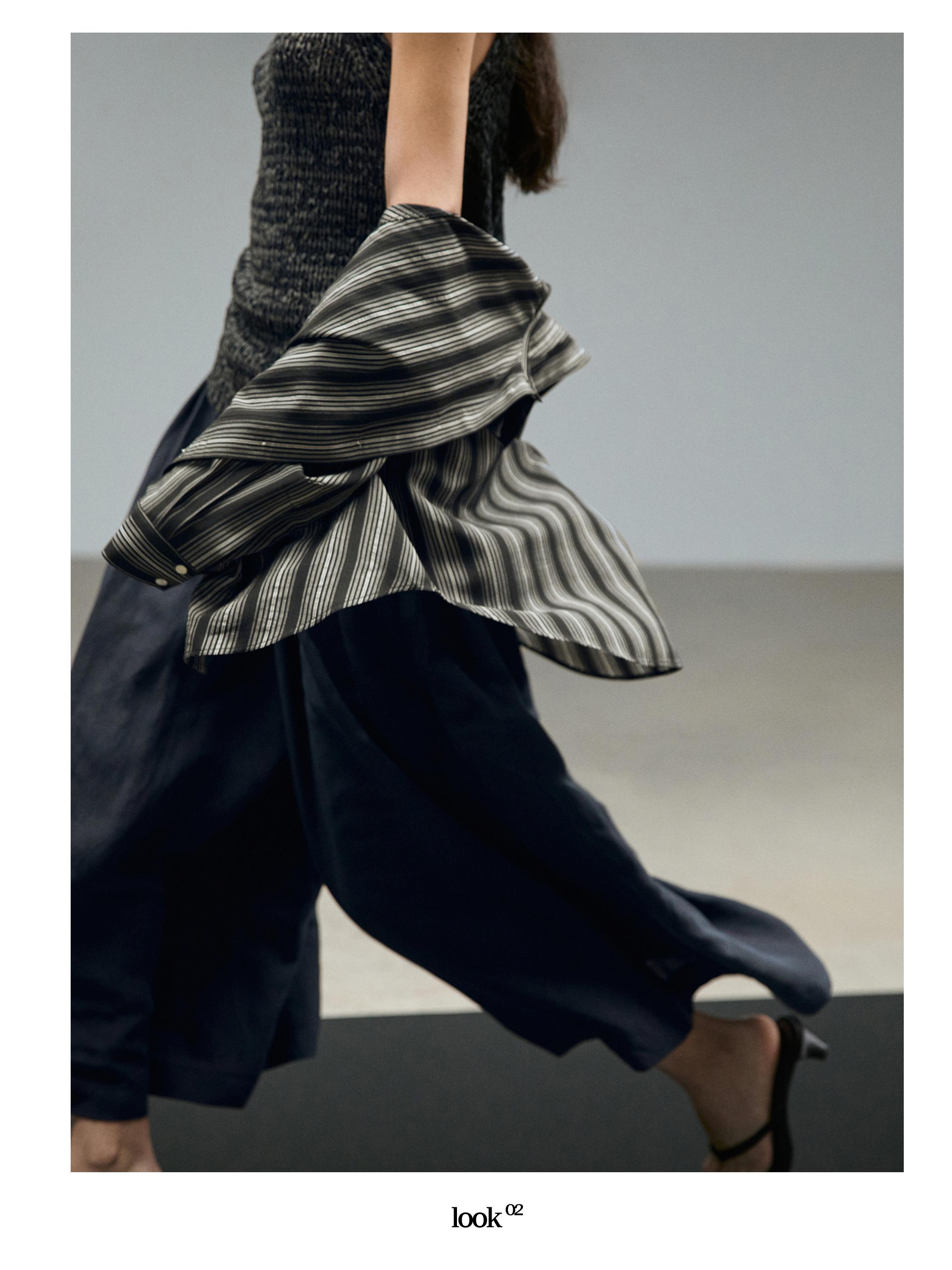 Plano medio de camisa a rayas en movimiento y pantalón oscuro amplio.