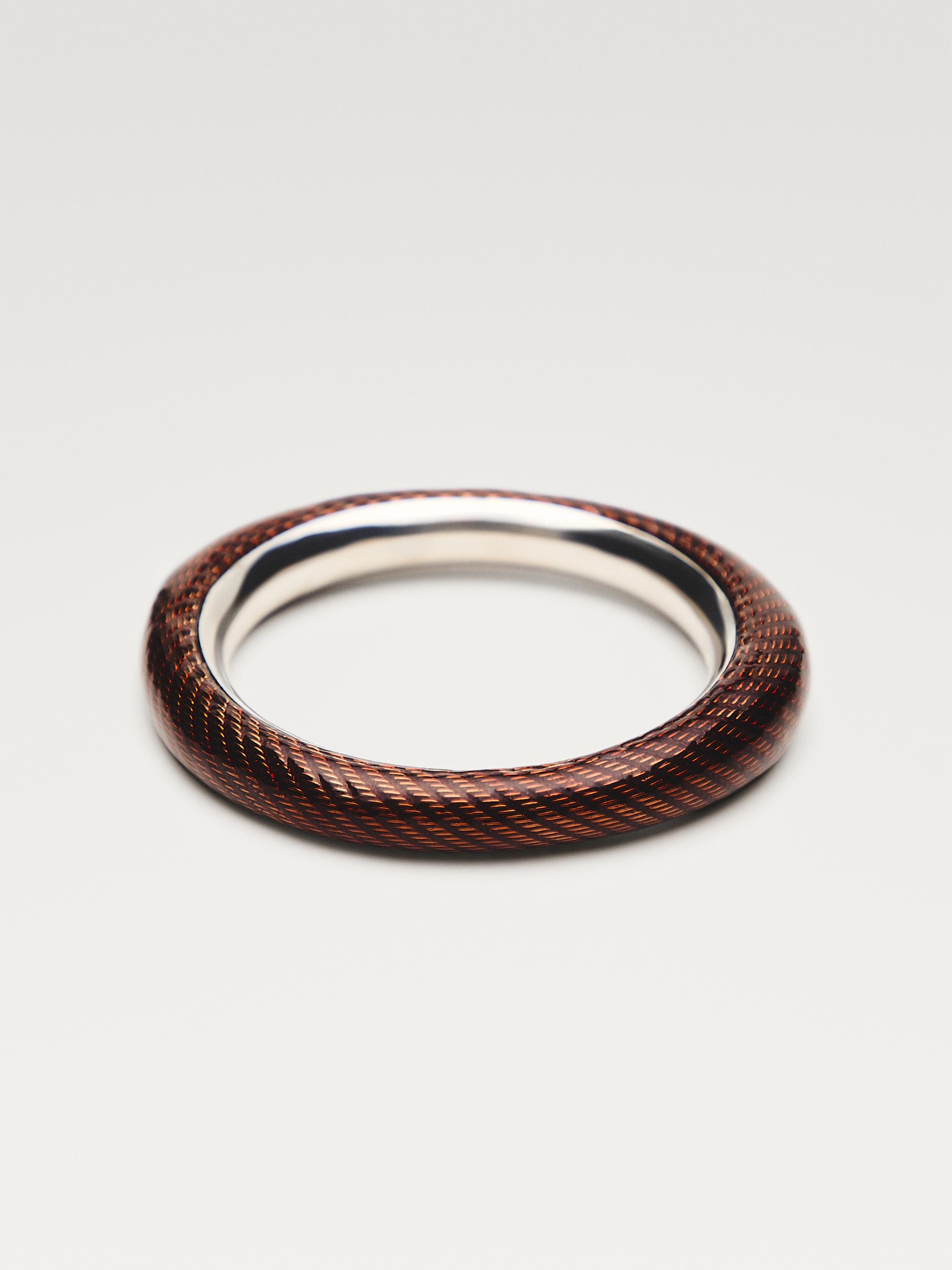Μπροστινή όψη ασημένιου βραχιολιού με πλεγμένο σχέδιο σε καφέ και μαύρους τόνους.