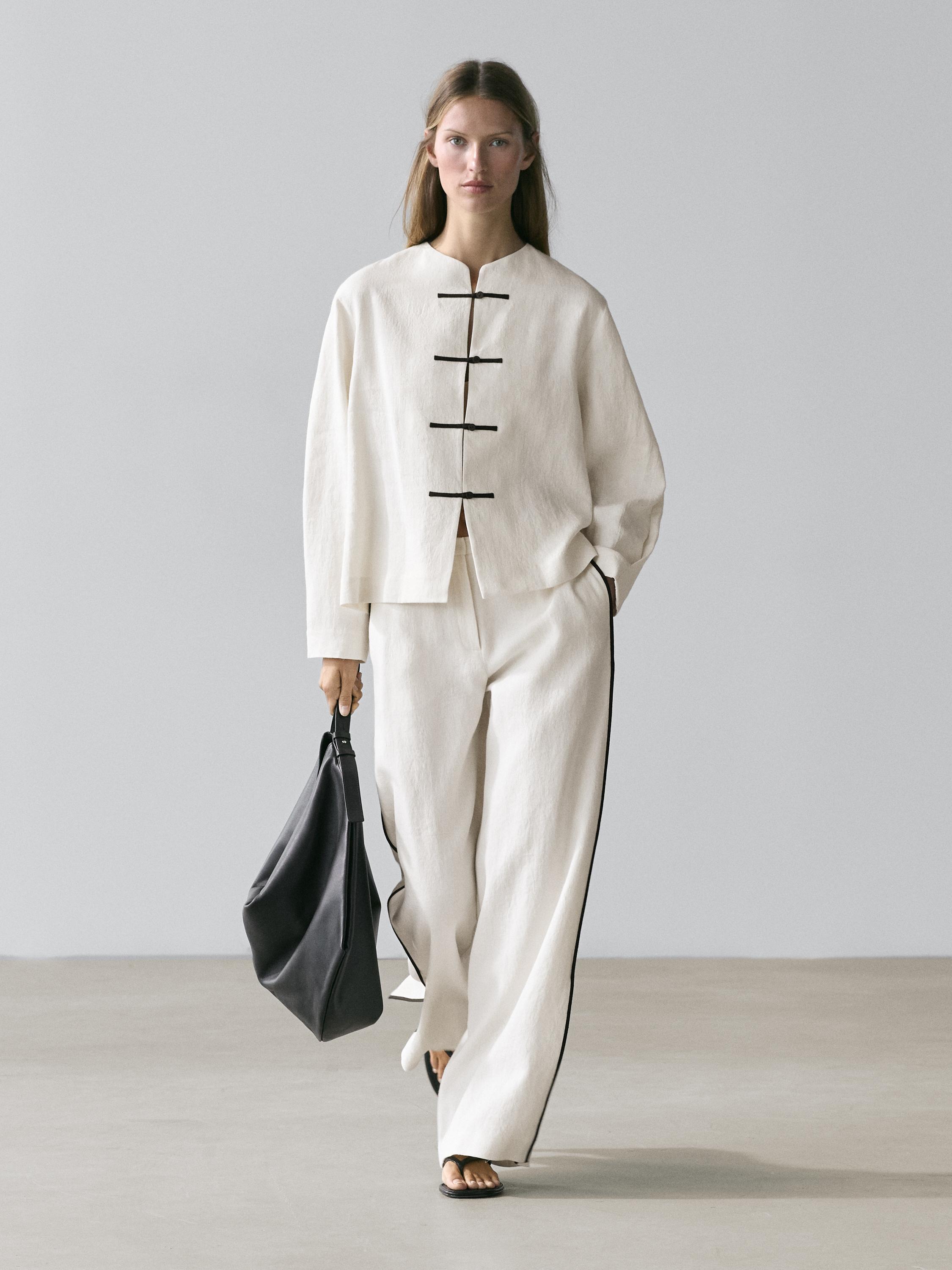 ชุดเสื้อเชิ้ตดิบติดกระดุมสีดำและกางเกงขายาวทรงหลวมเข้าชุดที่มีแถบสีดำด้านข้าง