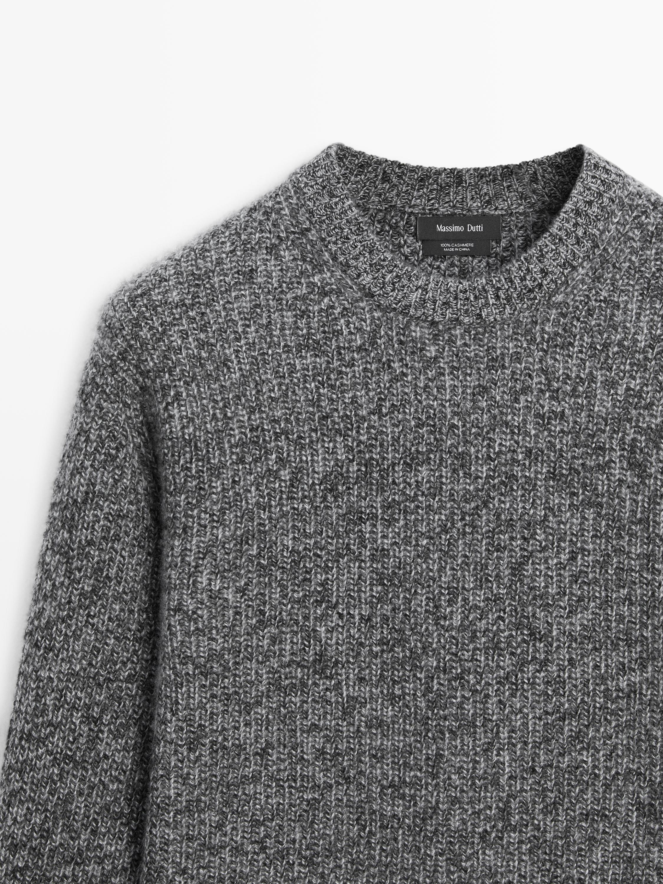 "Halbaufnahme eines melierten anthrazitgrauen Jerseys mit Rundhalsausschnitt und sichtbarem Etikett im Krageninneren."