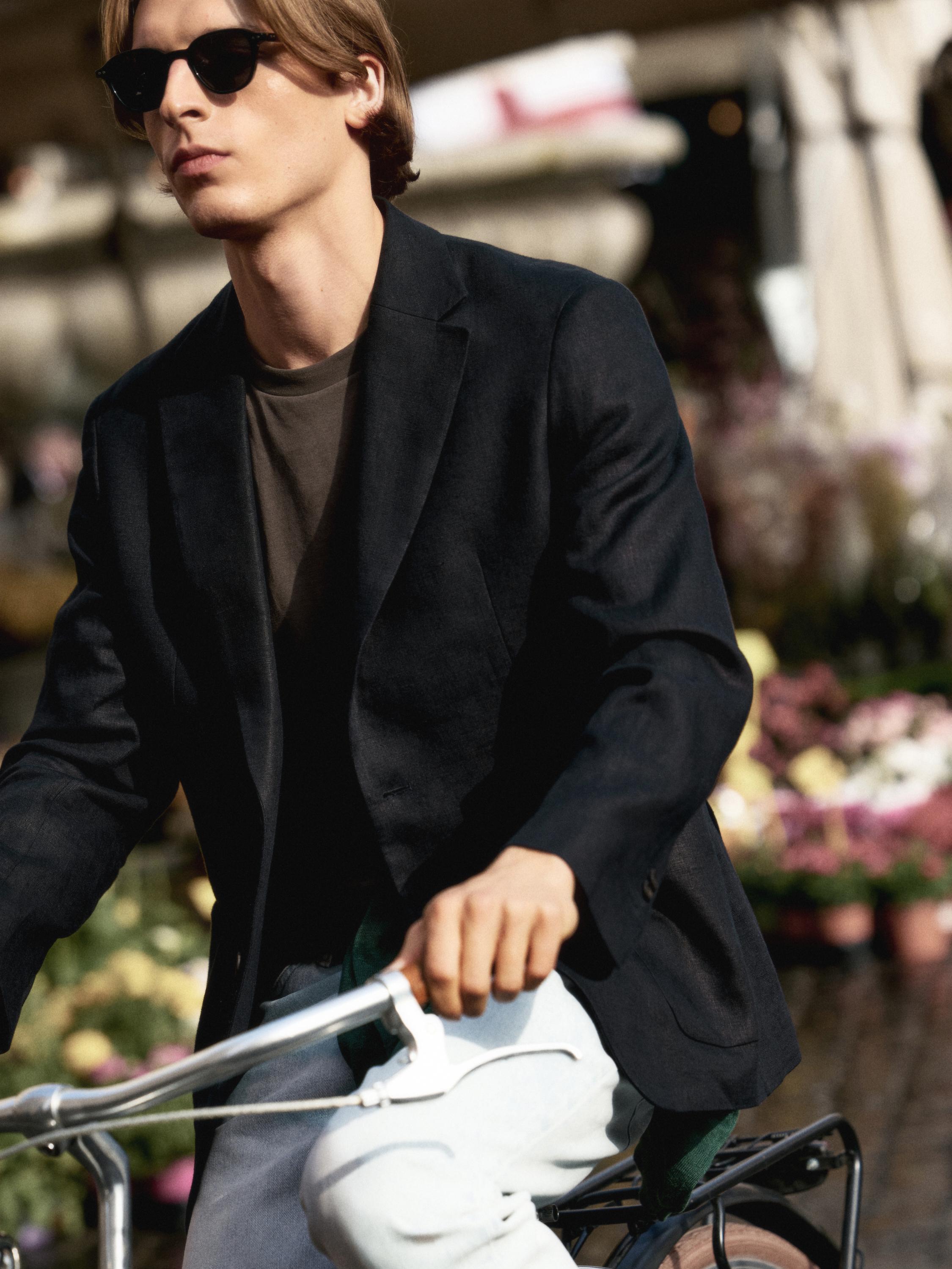 Plano medio de blazer negro con solapa clásica y camiseta gris debajo.