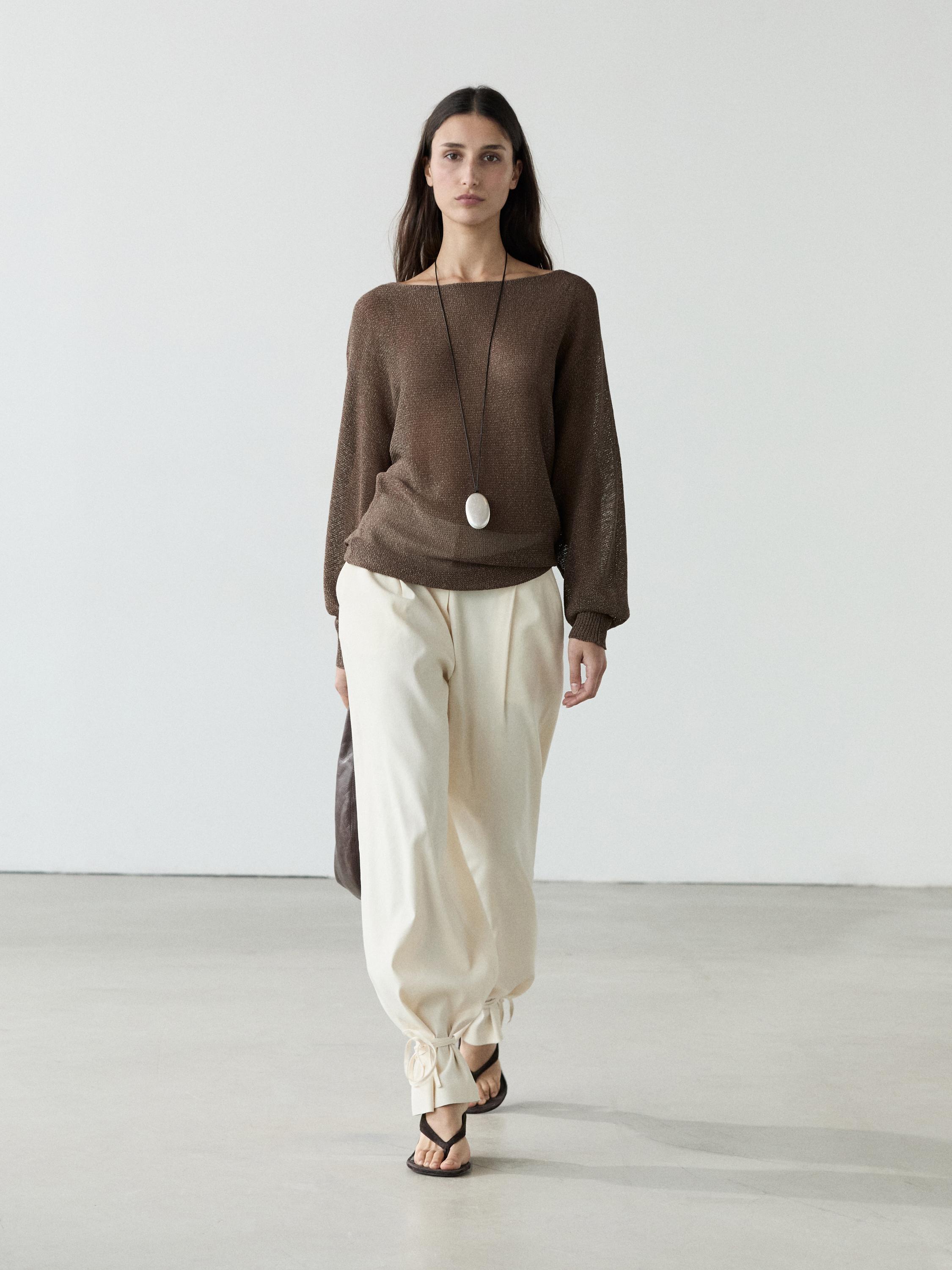 Vloeiende gebreide bruine jersey set en beige broek met strikjes bij de enkels.