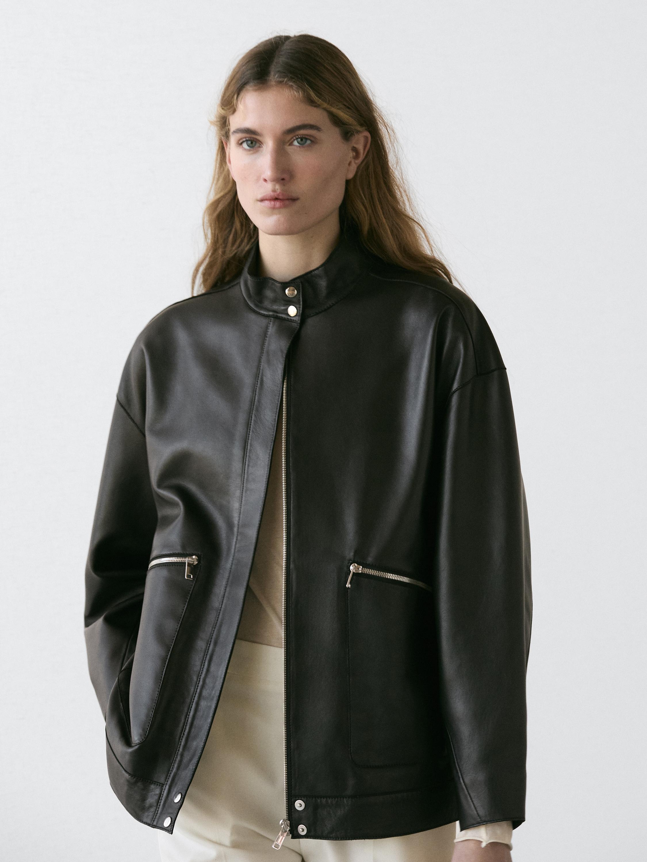Black jacket set with a front zipper and side pockets with closure, over light-colored pants.