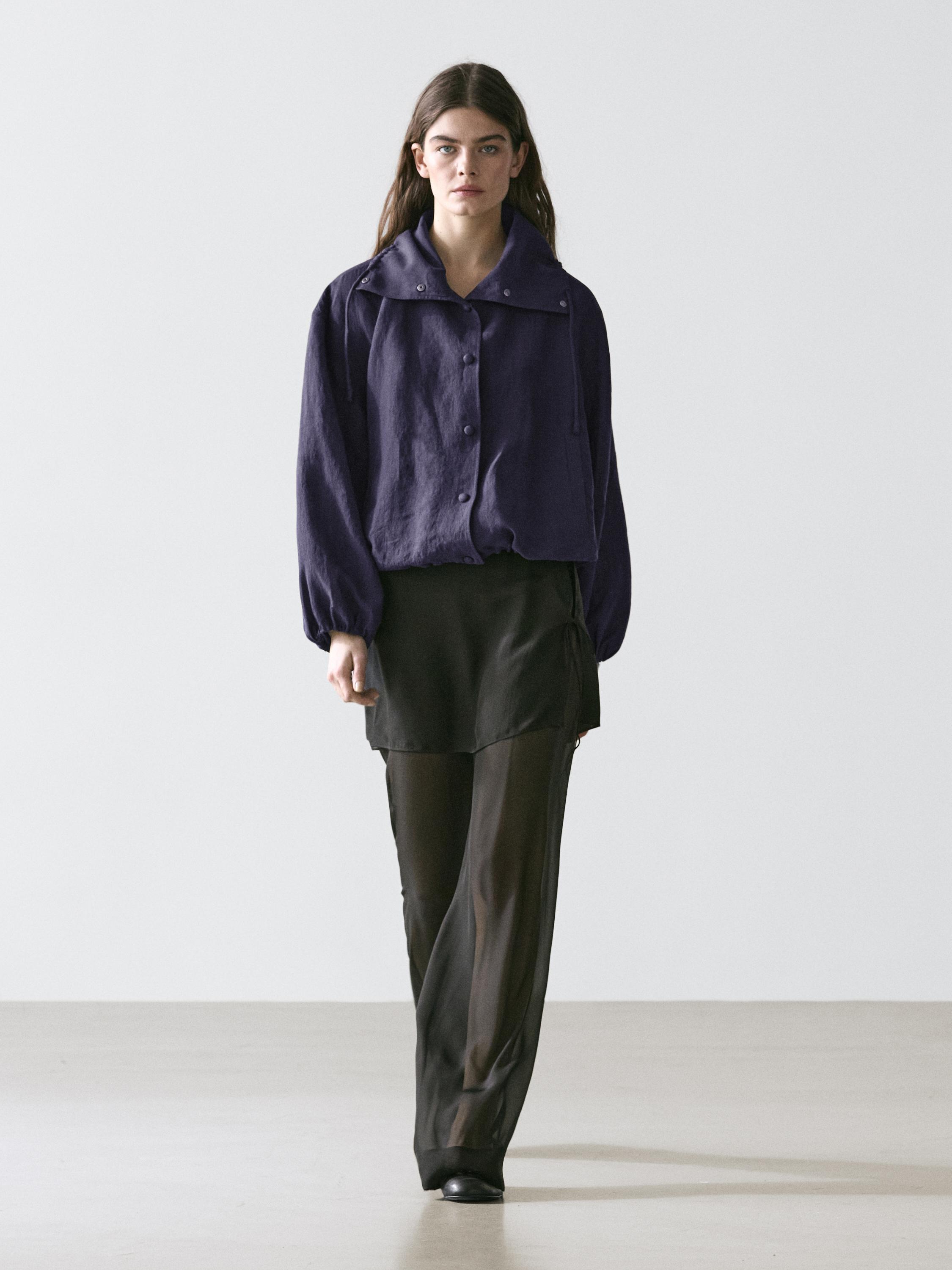 Geniş yakalı ve düğmeli indigo bomber ceket, siyah mini etek ve siyah transparan pantolon takımı.