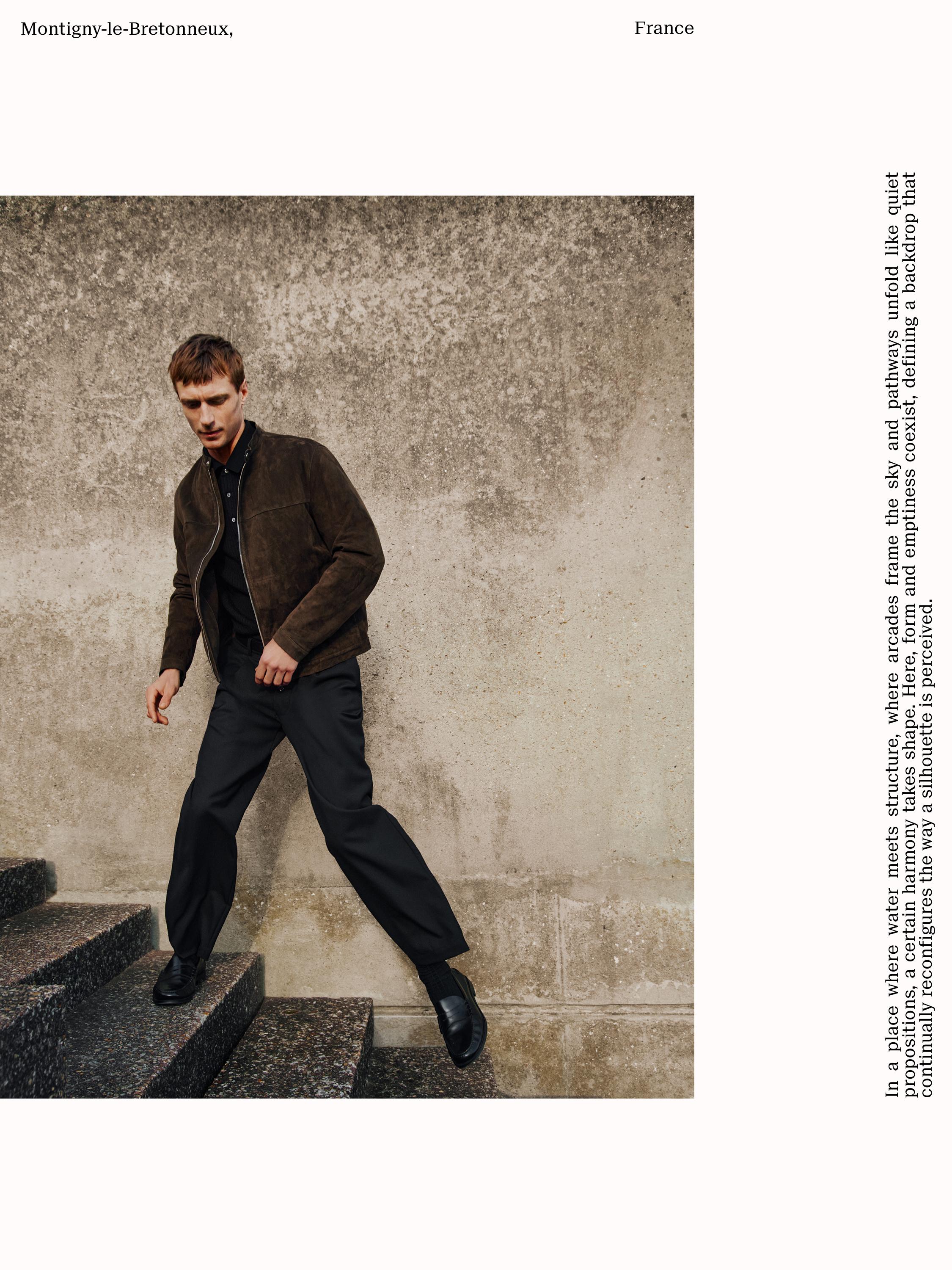 Conjunto de chaqueta marrón con cremallera y pantalones negros anchos.