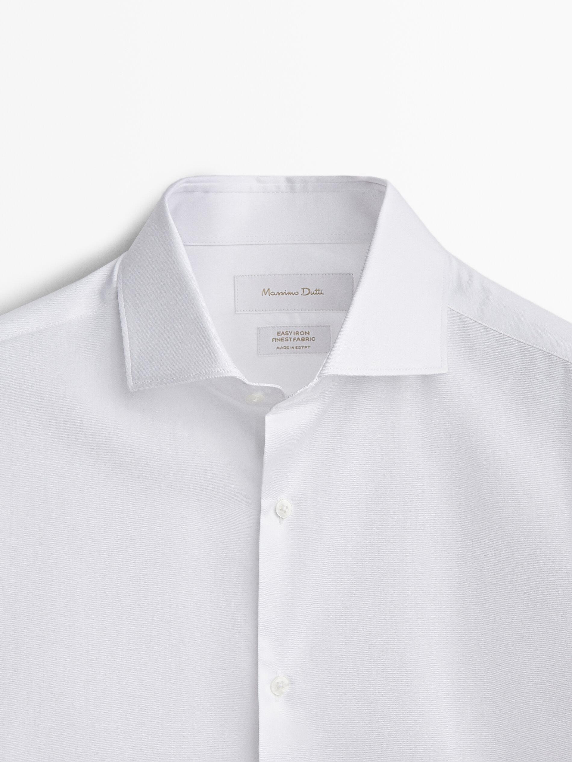 Plan moyen de la partie supérieure d'une chemise blanche avec col et boutonnière visibles.