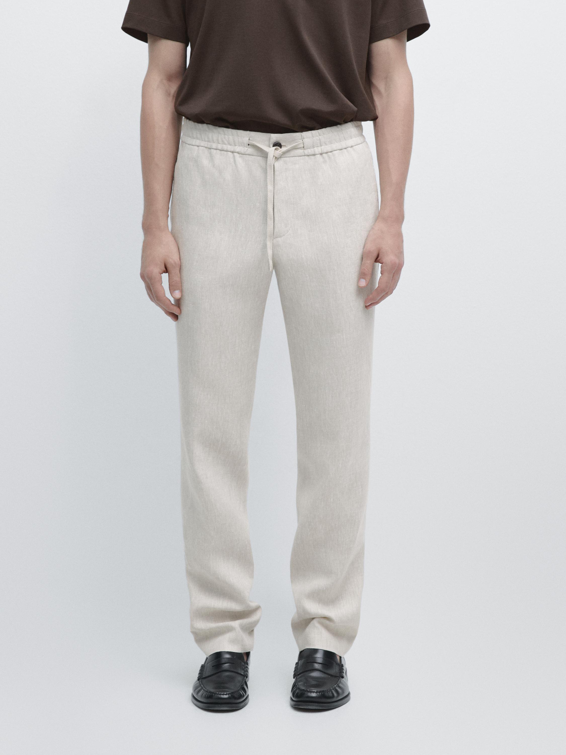 Conjunto de pantalón jogger arena con cintura elástica y cordón, bolsillos laterales, cierre de botón y cremallera.