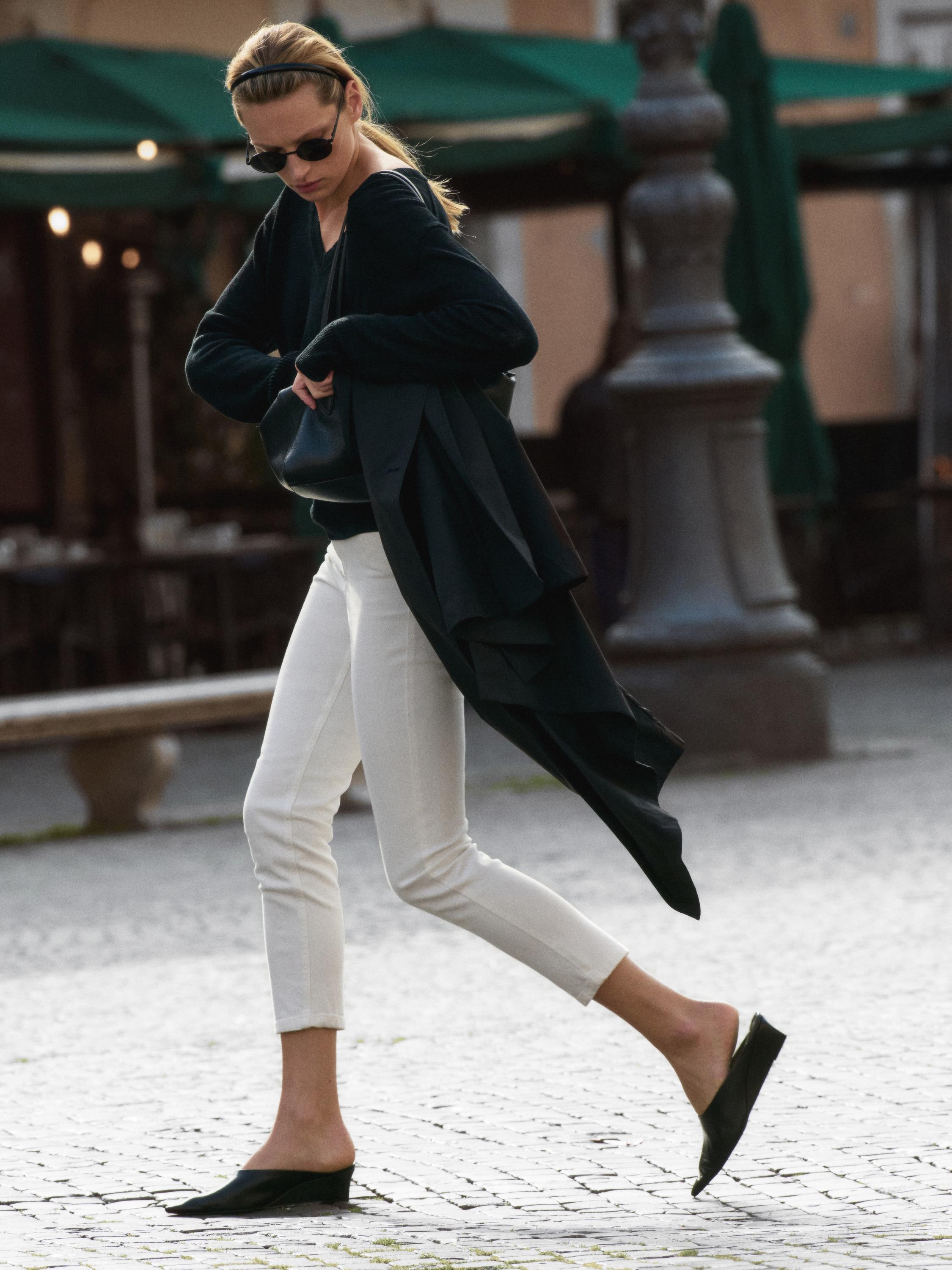 Schwarzes Pullover-Set, weiße, enge Hose und schwarze Schuhe ohne Absatz.