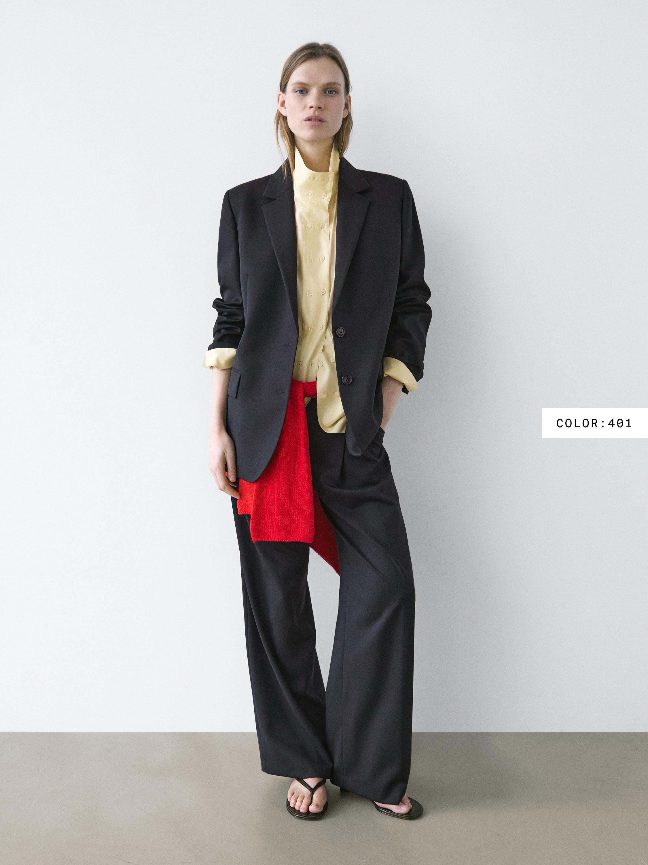 Conjunto de blazer negro, camisa amarilla, pantalones anchos negros y bufanda roja.