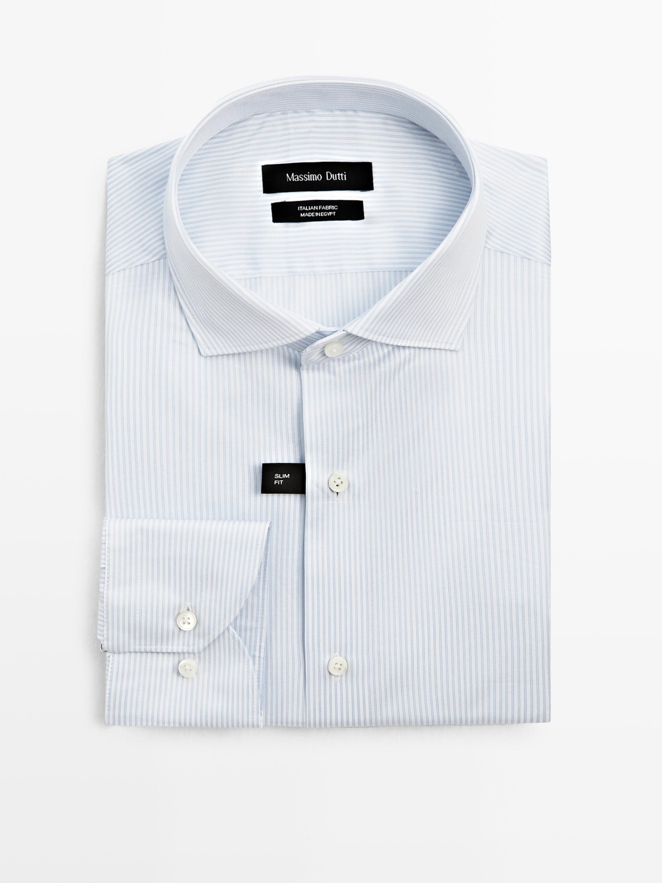 Vorderansicht eines hellblauen, schmal geschnittenen Hemdes mit feinen Streifen, klassischem Kragen und geknöpften Manschetten. Sichtbarer Text: „SLIM FIT“.