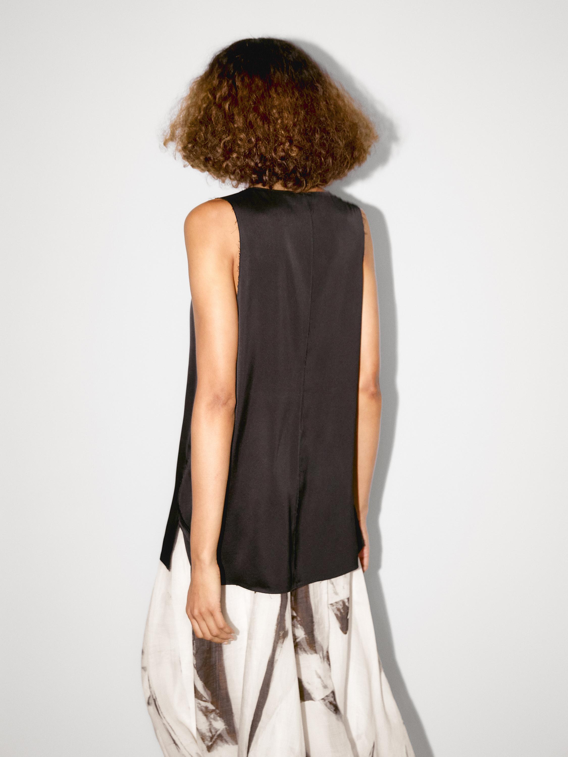 Vue arrière d'un long chemisier noir sans manches sur une jupe à imprimé abstrait.