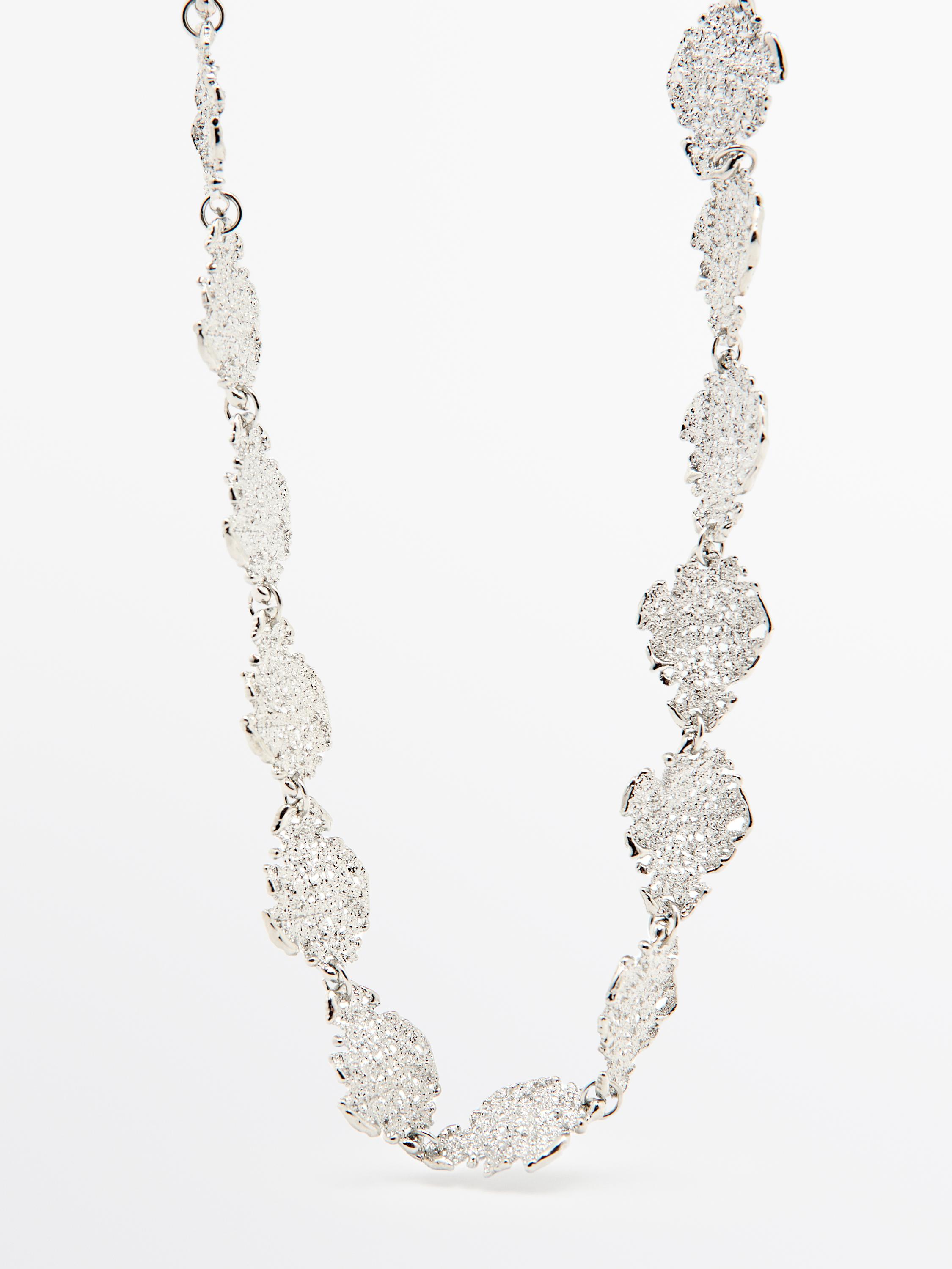 Колье-бижутерия серебристого цвета с текстурированными и блестящими звеньями.