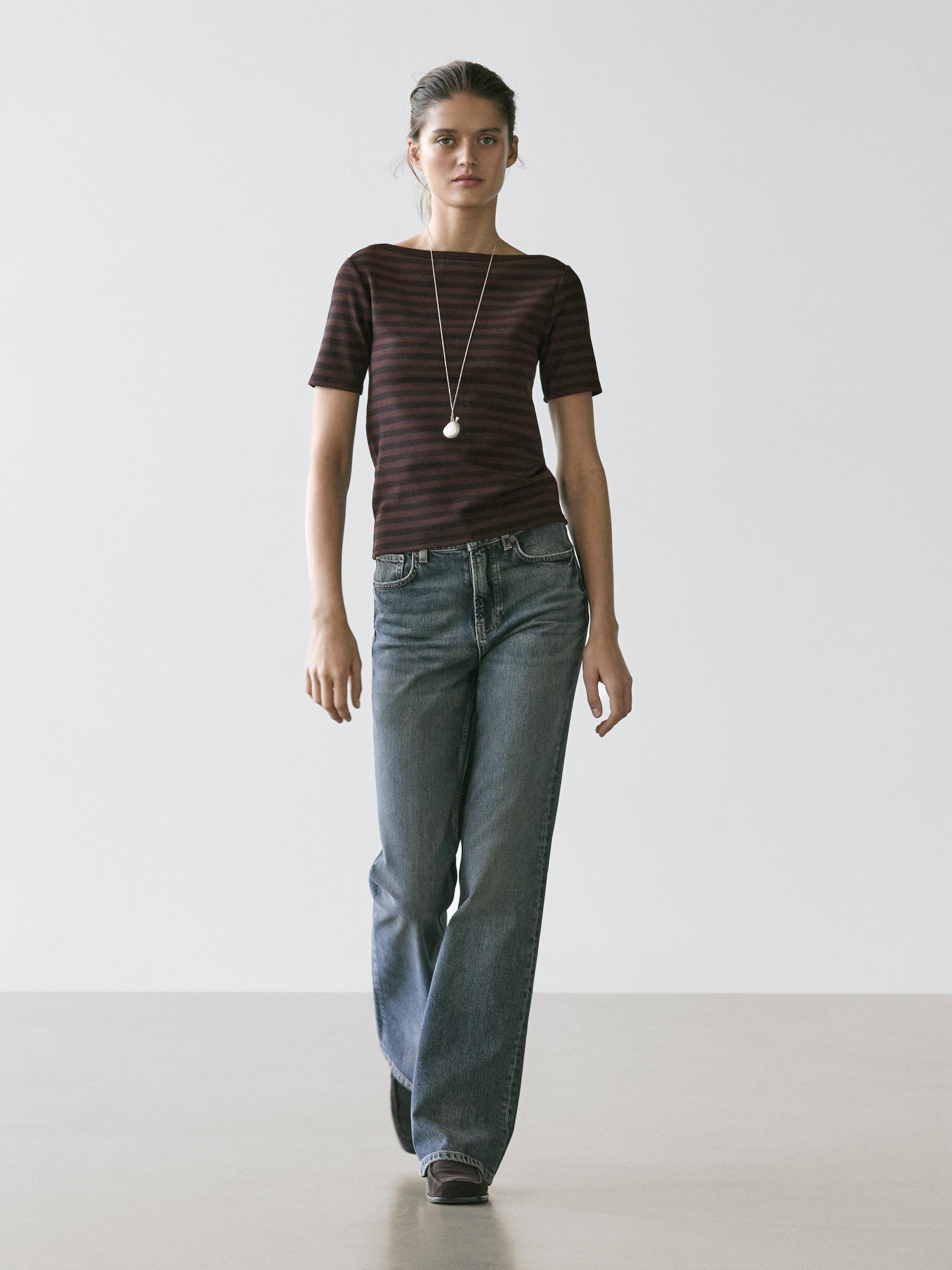 Conjunto de camiseta marrón de rayas con cuello barco y mangas cortas, combinada con jeans de corte recto y bolsillos laterales.