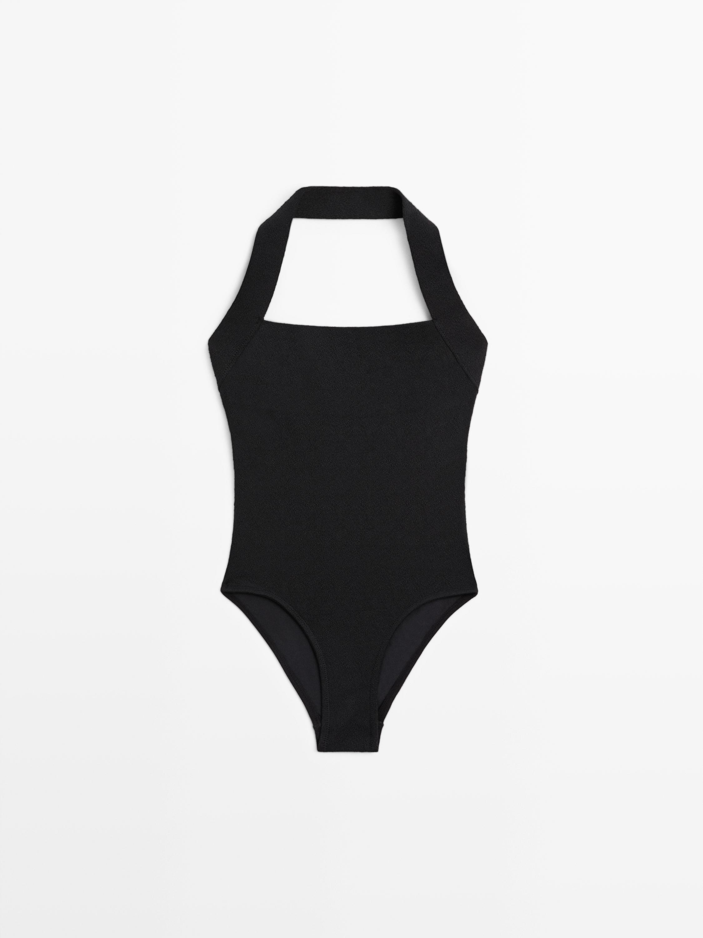 Vista frontal de traje de baño negro con escote halter y corte de pierna alta.