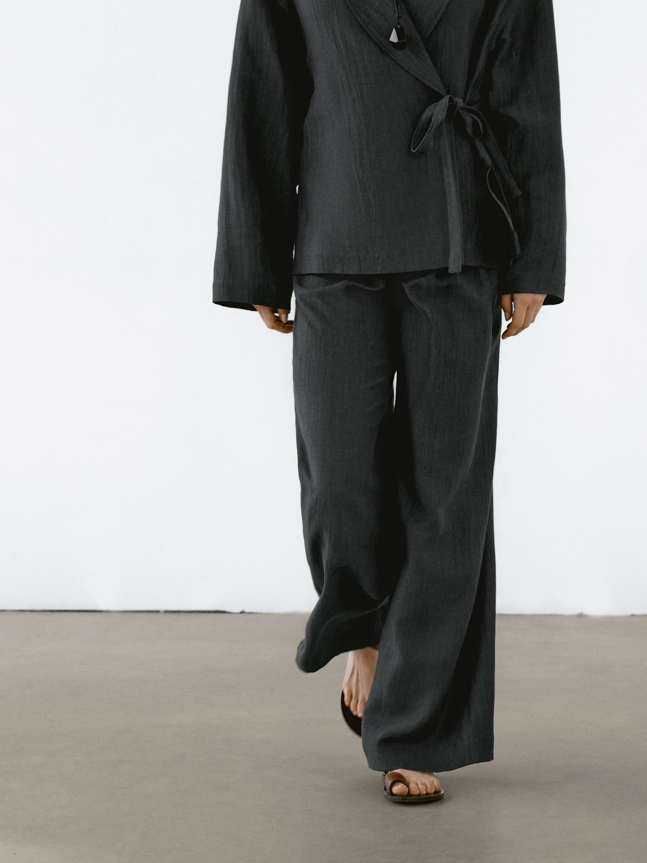 Conjunto de chaqueta negra con lazo y pantalones anchos a juego.