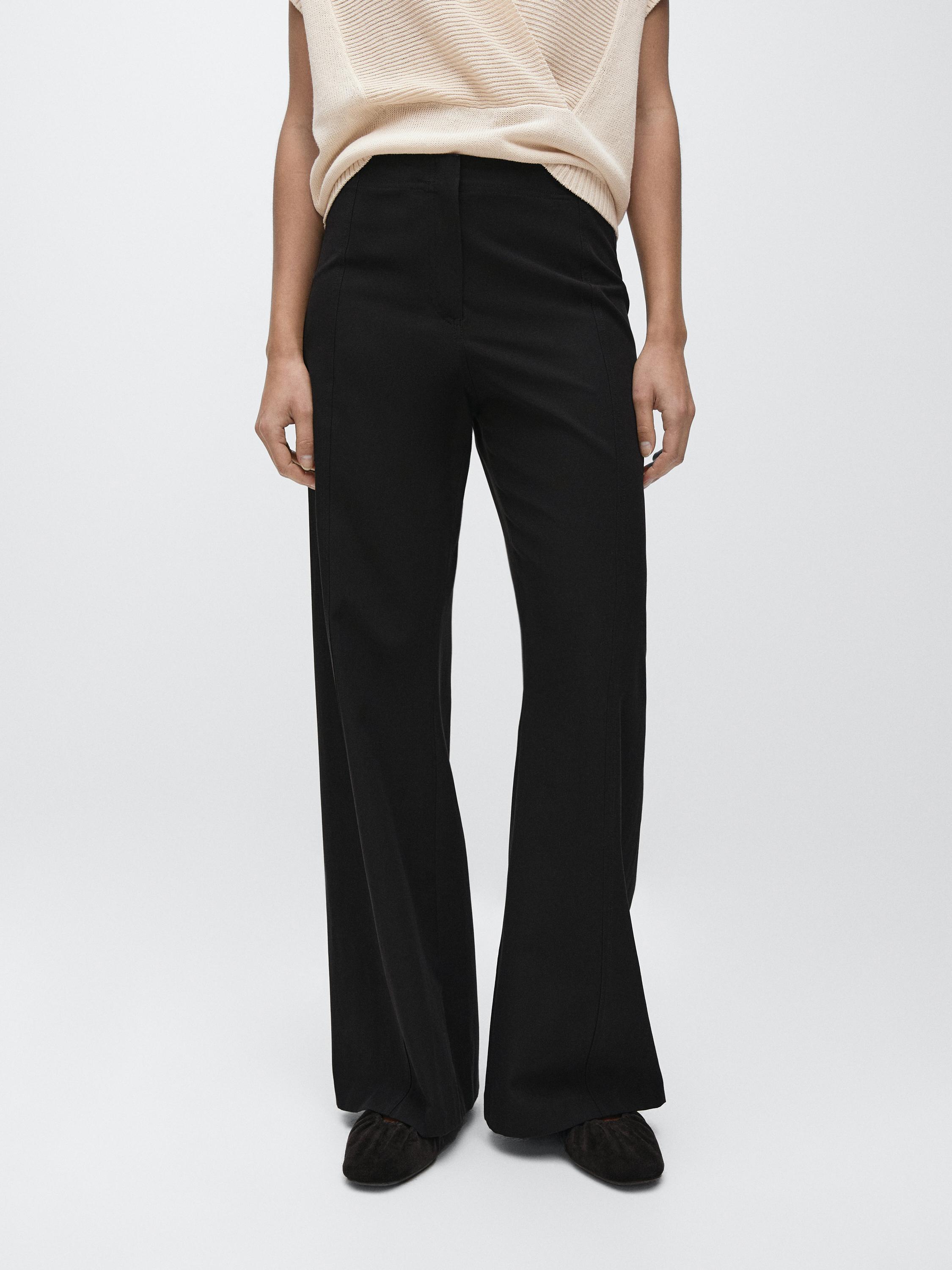 Black flare-fit pants set with a high waist and a sleeveless beige blouse.