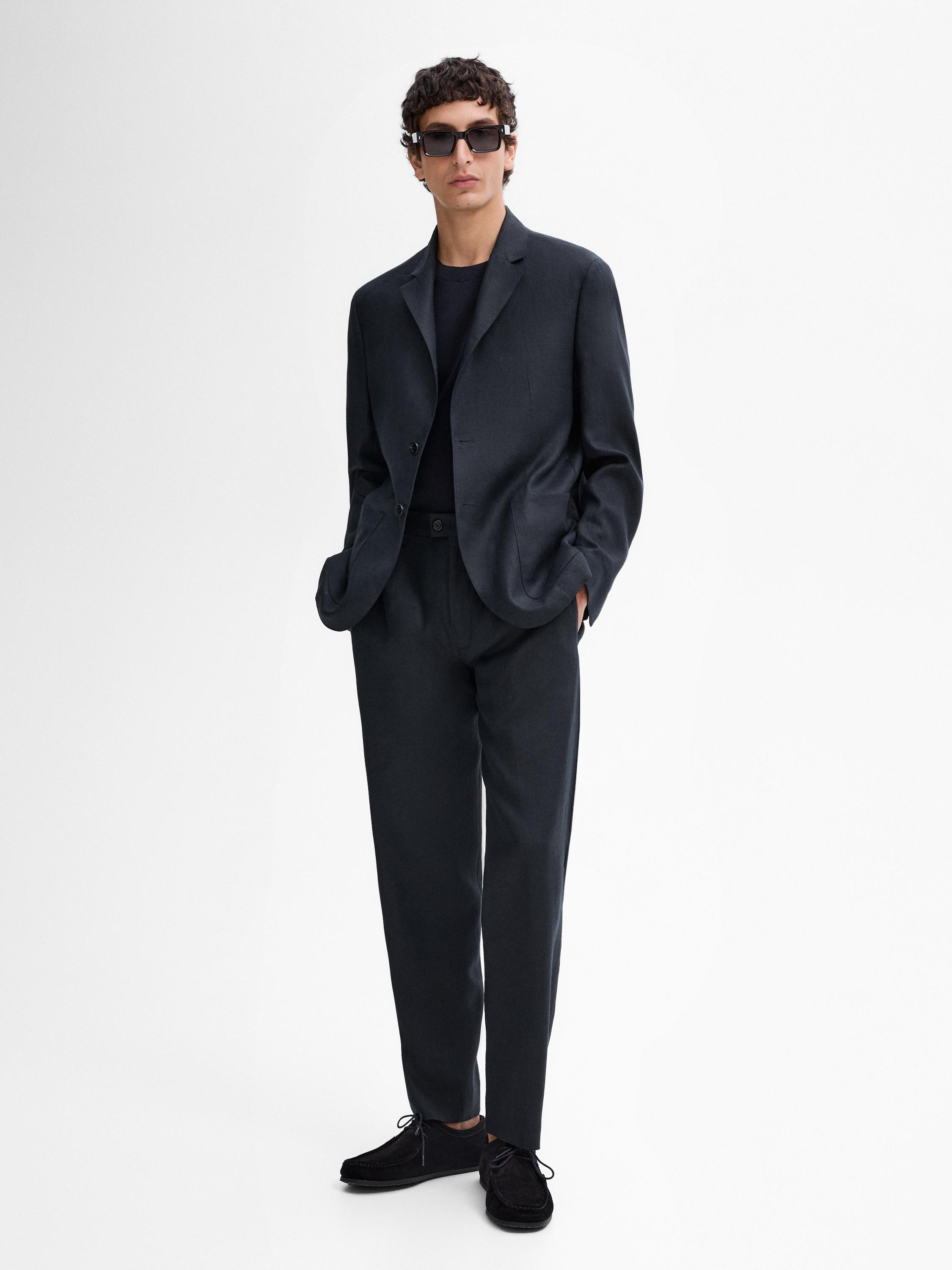 Ensemble de costume noir avec veste et pantalon, t-shirt noir et chaussures noires.