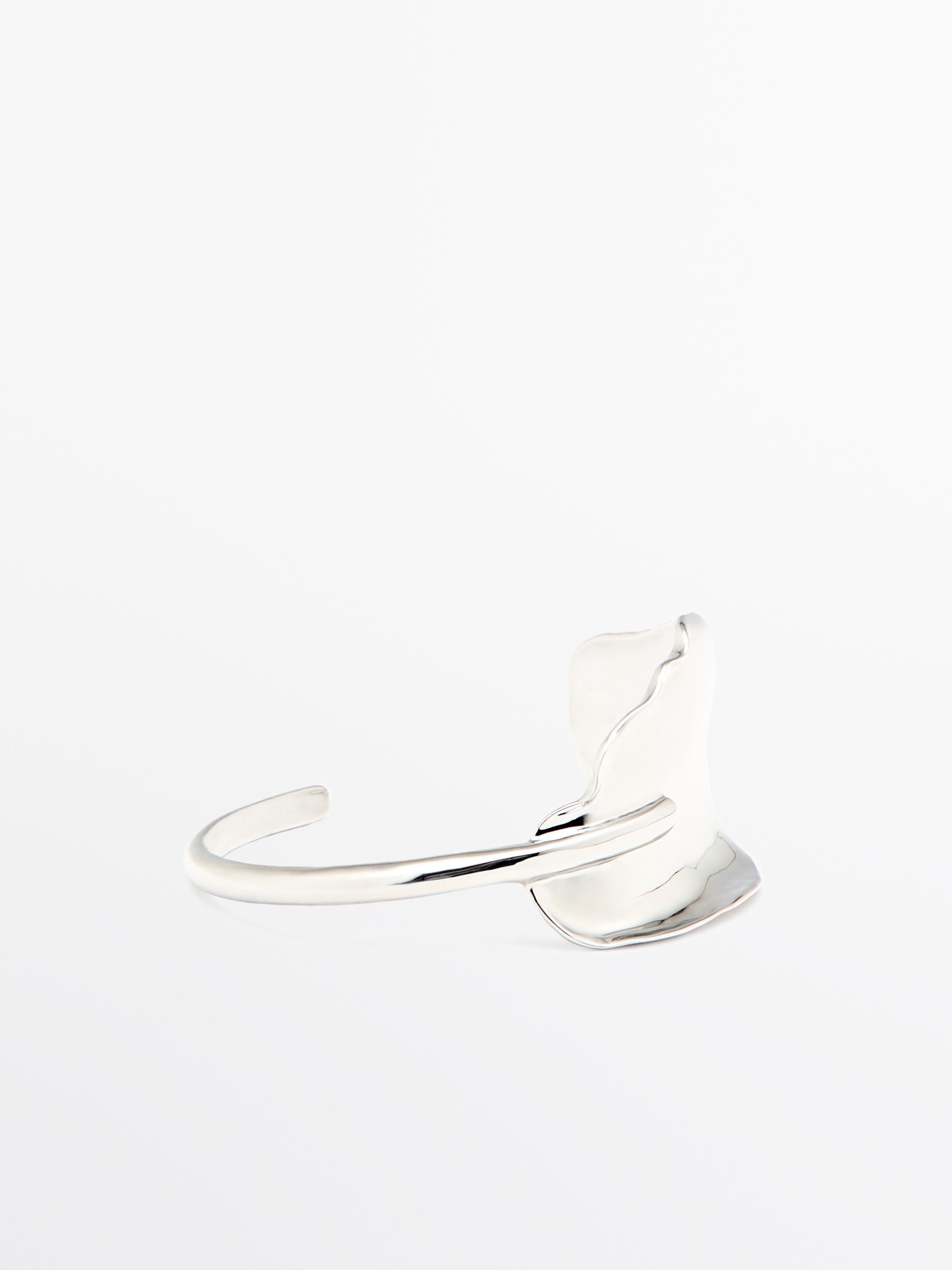 Pulseira larga de prata com design assimétrico e textura ondulada.