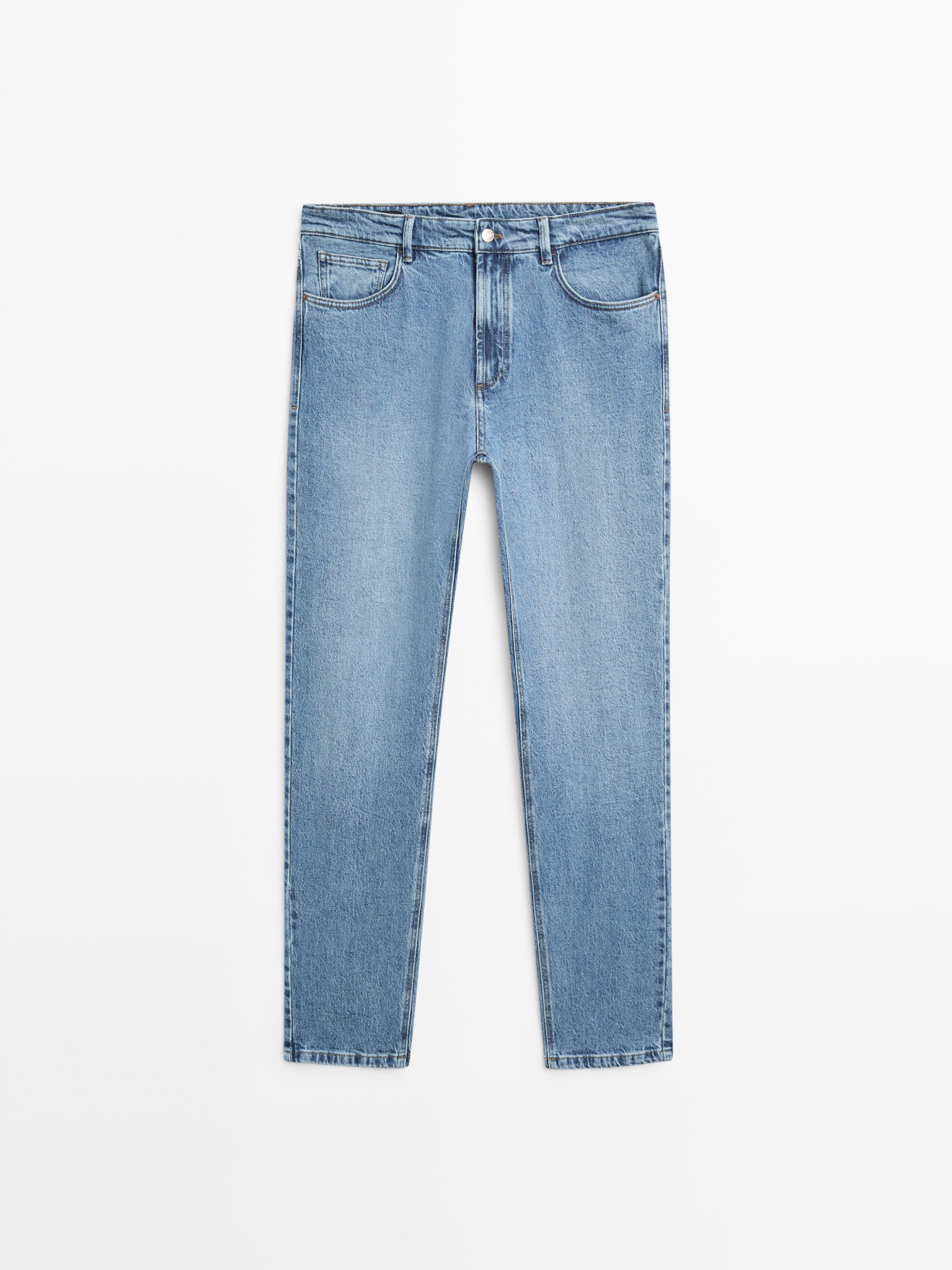 Vista frontal de calças de ganga azuis com bolsos à frente e atrás, fecho de botão e fecho éclair.