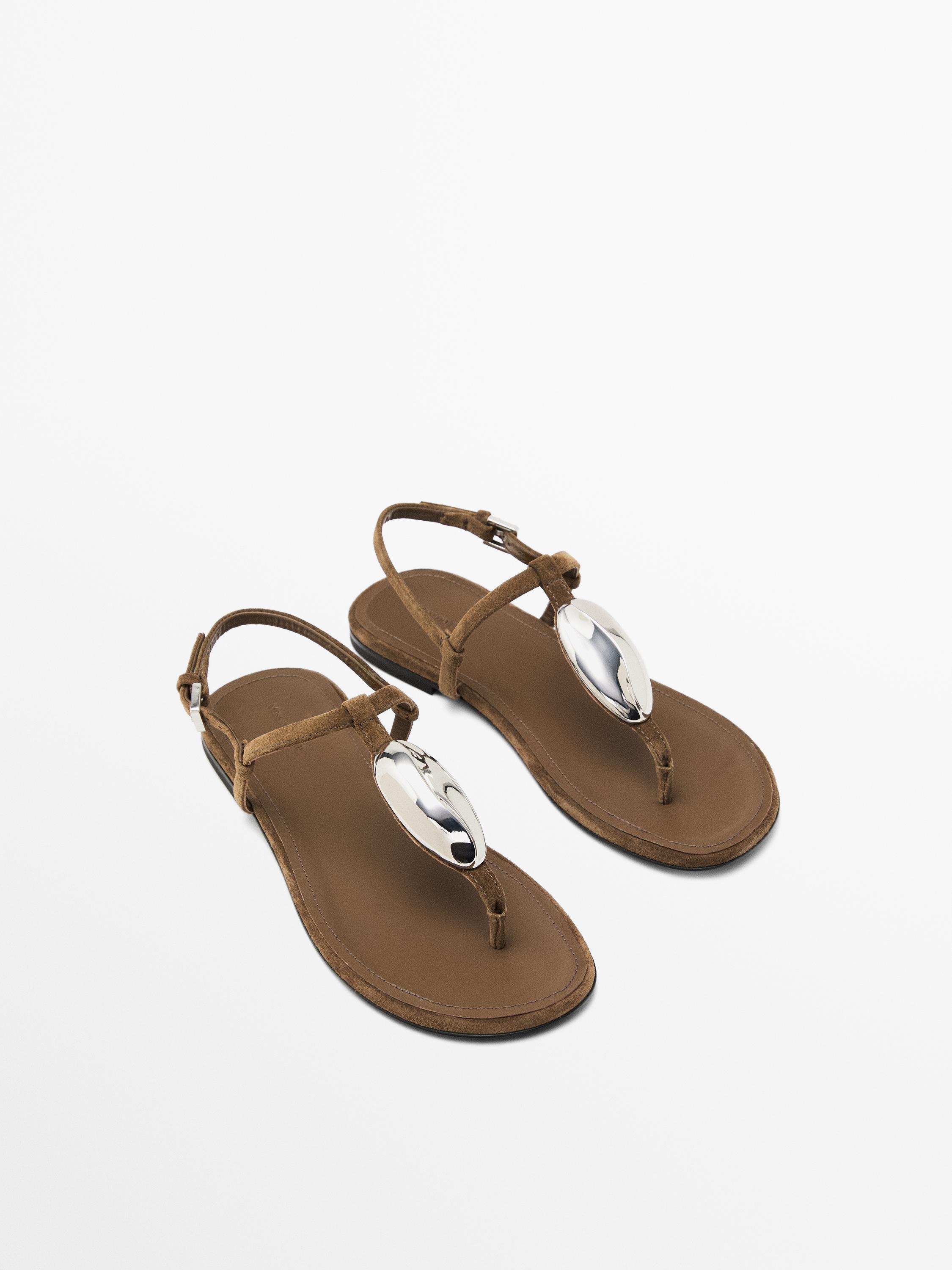 Top-down view of brown sandals with silver metallic detailing on the center strap and adjustable ankle closure.