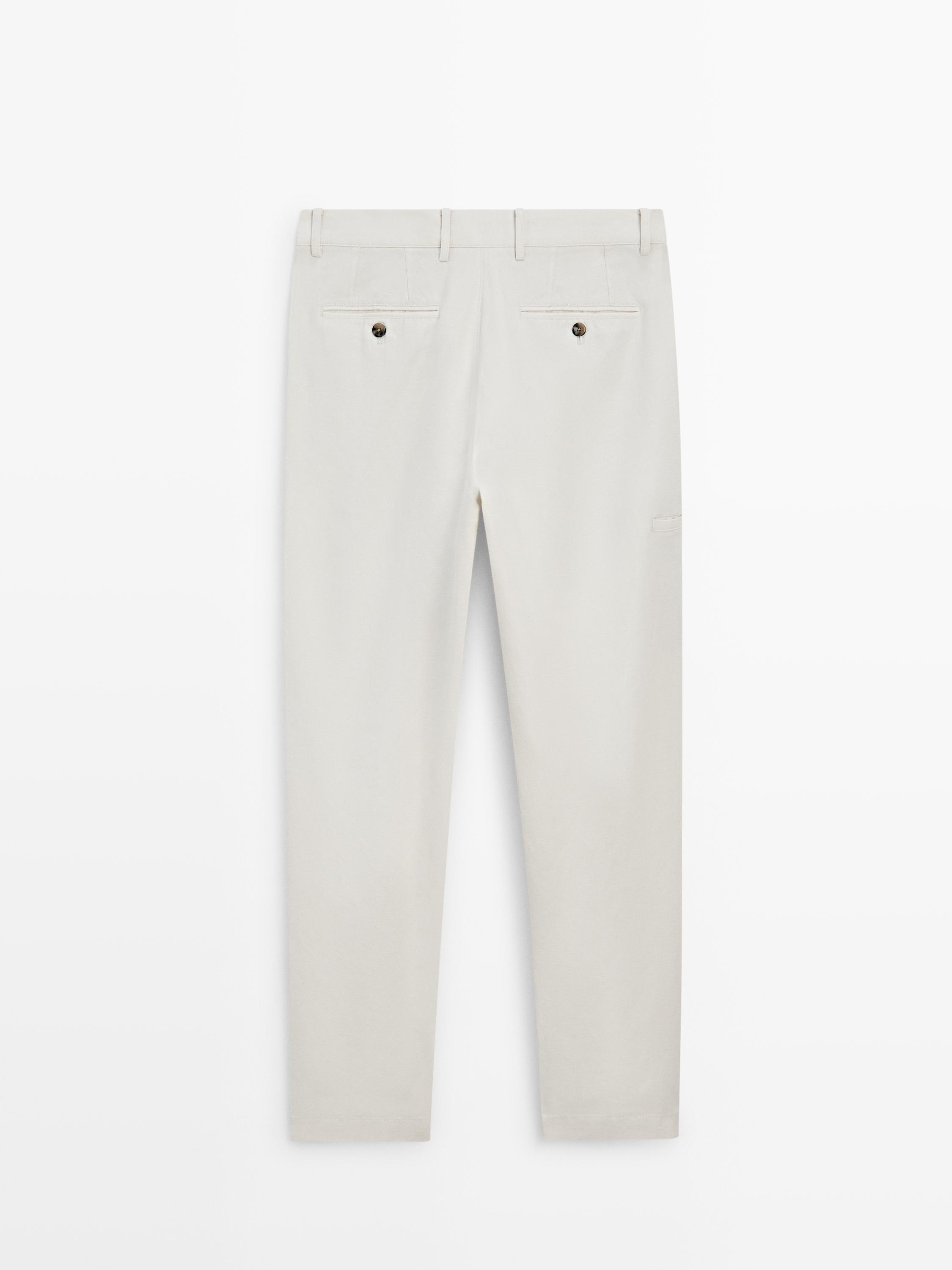 Vista posterior de pantalons blanc trencat amb butxaques posteriors amb botó i travetes per a cinturó.