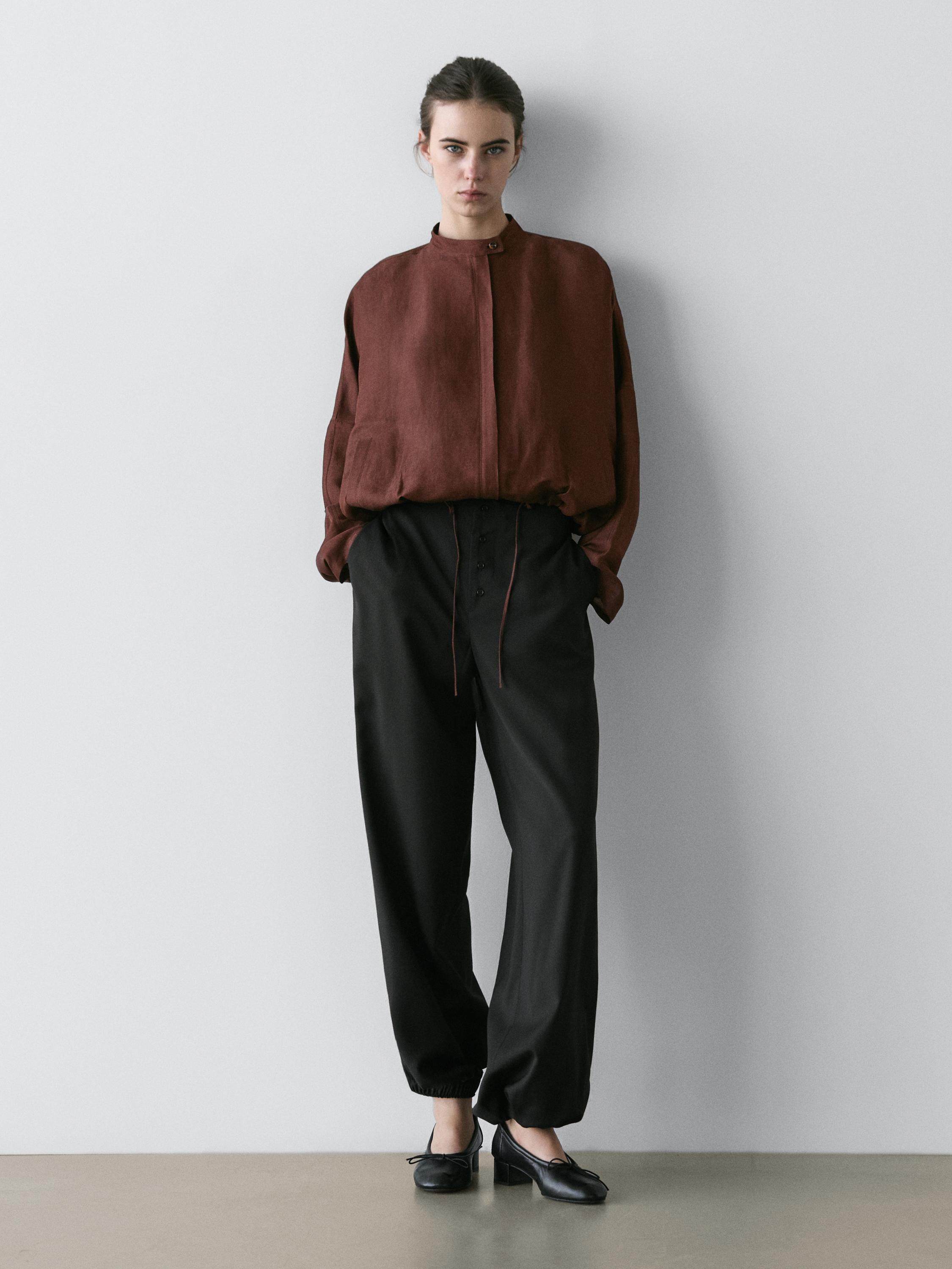 ชุดเสื้อแจ็คเก็ตบอมเบอร์สีน้ำตาลแบบมีซิปด้านหน้าและกางเกงขายาวสีดำทรงขากว้าง