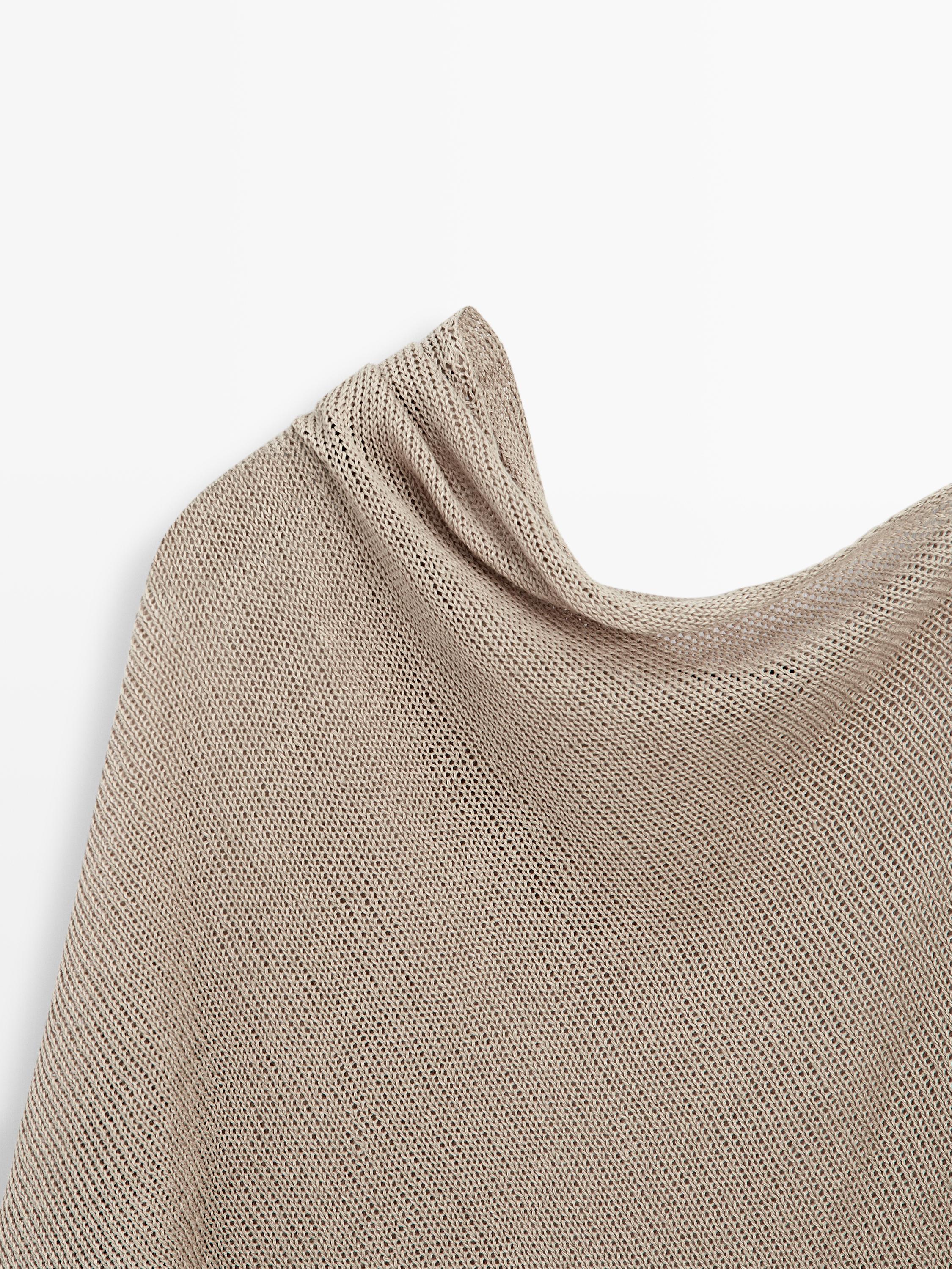 Detalle de la parte superior de un top de manga larga en color piedra, con tejido de punto y caída suave.