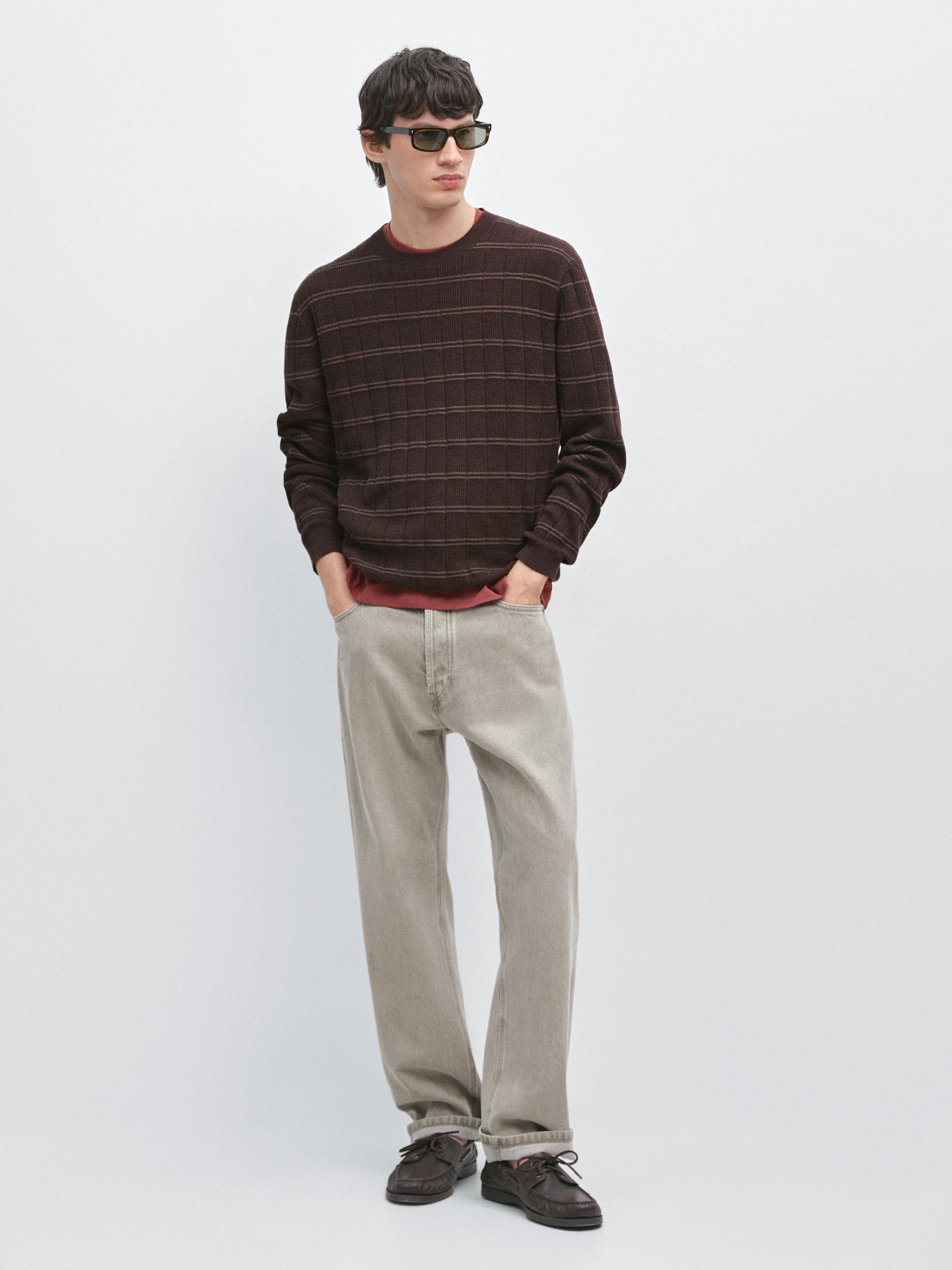 Conjunto de camisola castanha com padrão xadrez e calças bege.